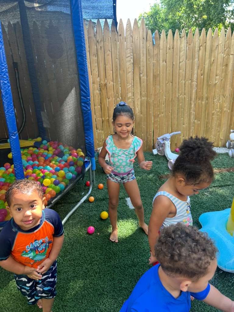 Four children playing in an outdoor area with a ball pit