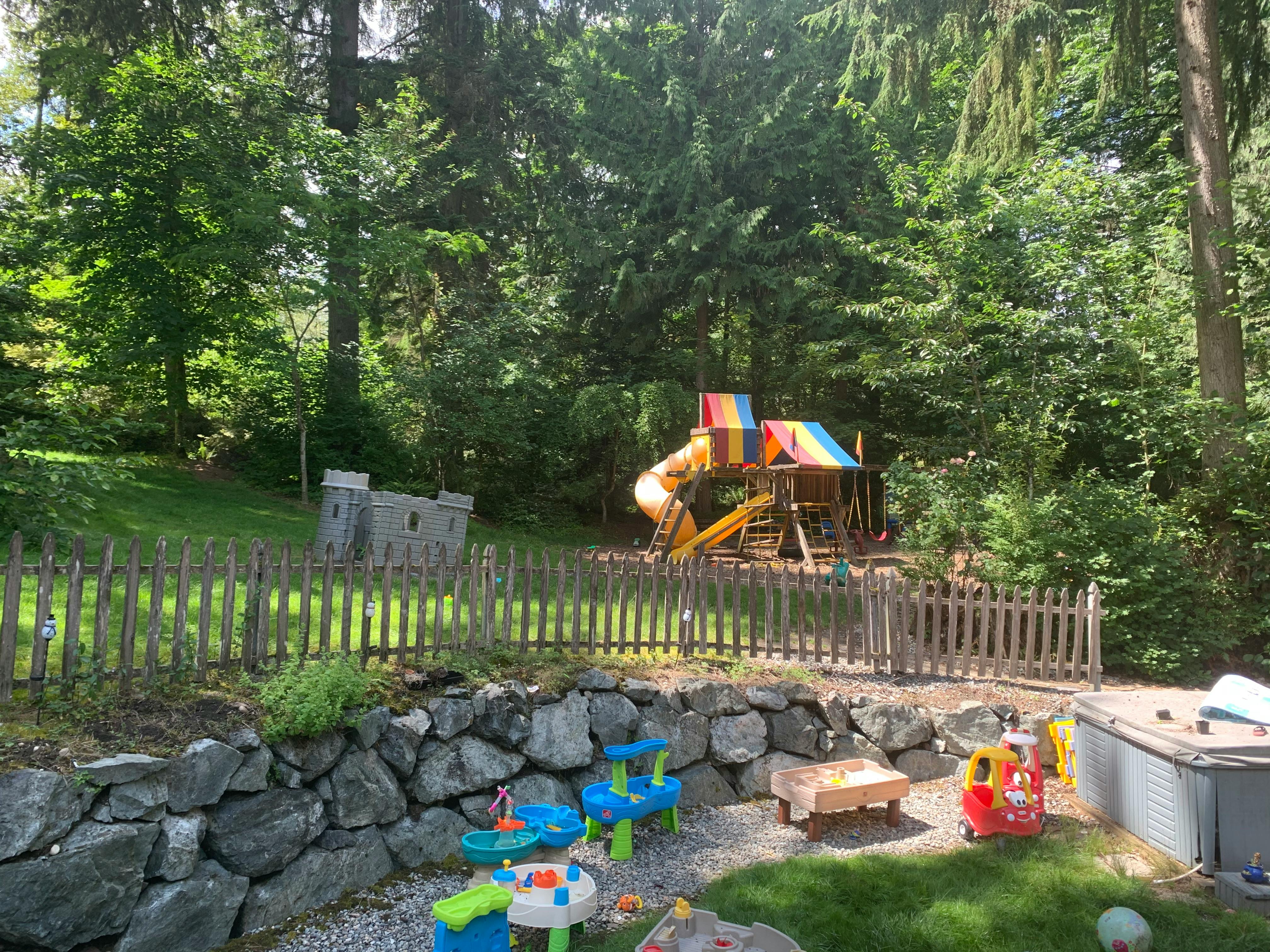 Playground with wooden fence and slide in a wooded area