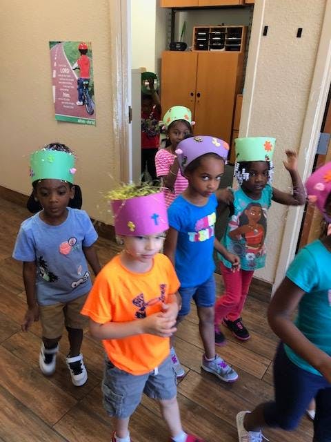 Children wearing colorful hats walking indoors