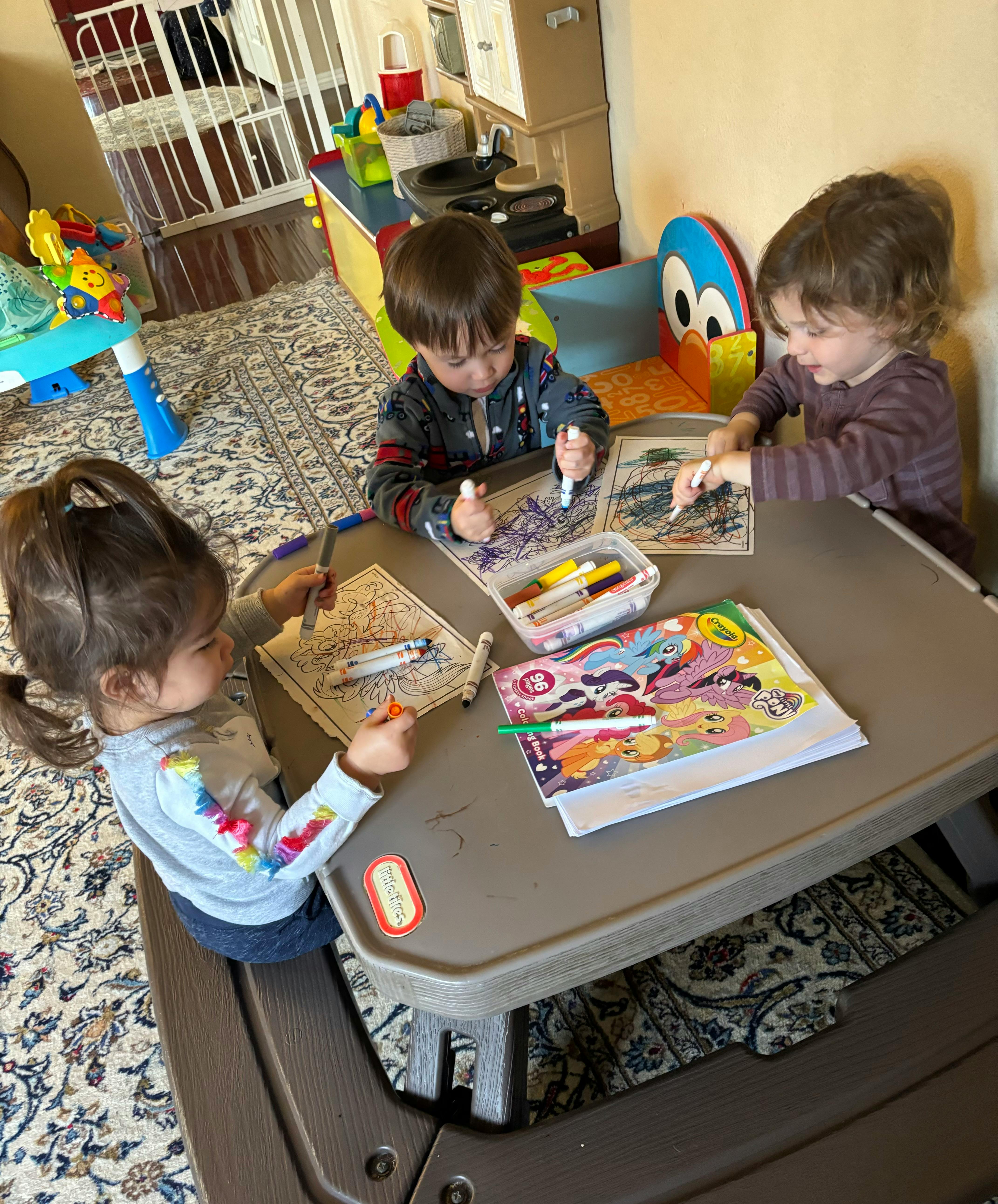 Three children drawing at a table