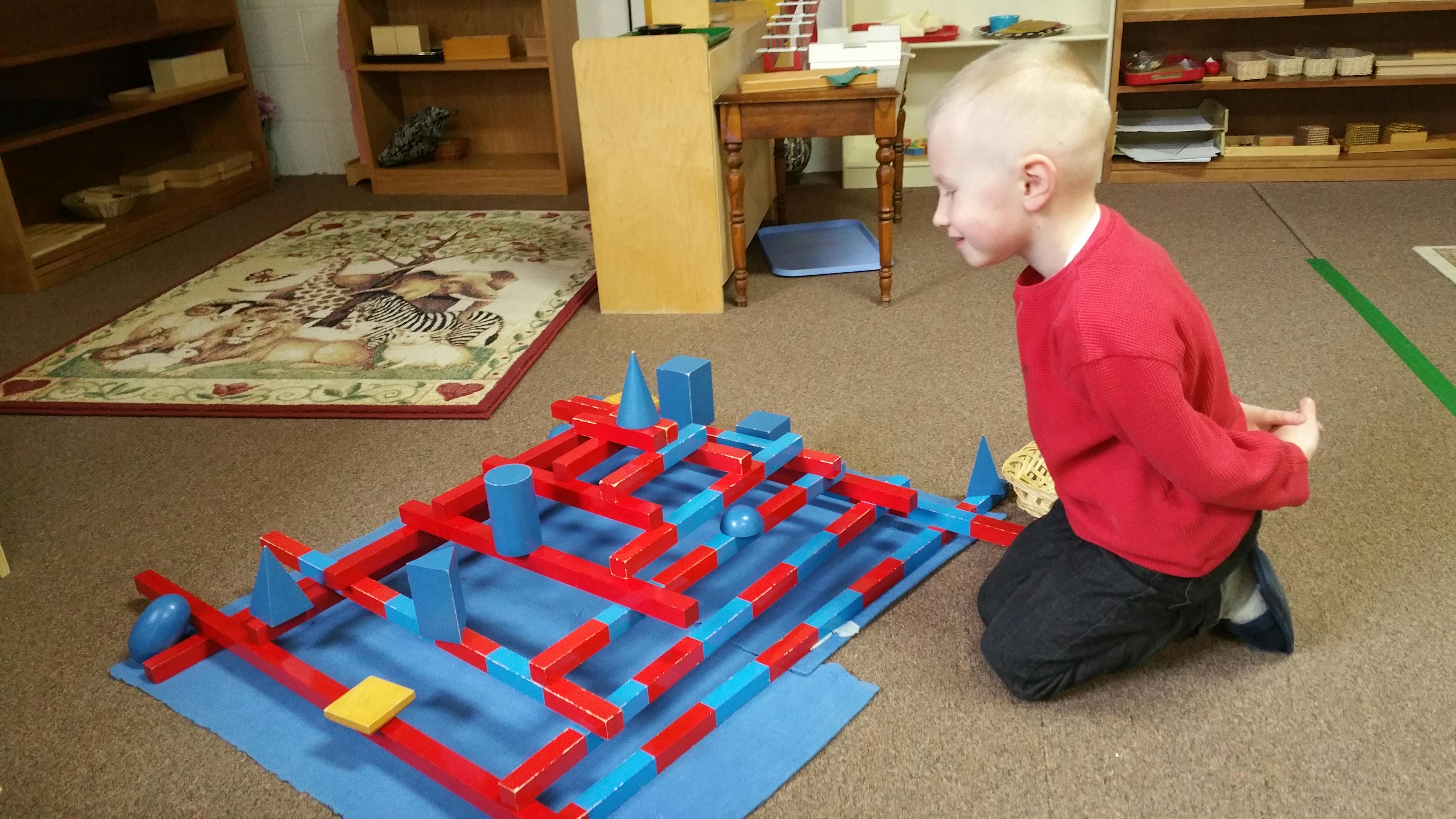 Child kneeling and looking at a construction toy