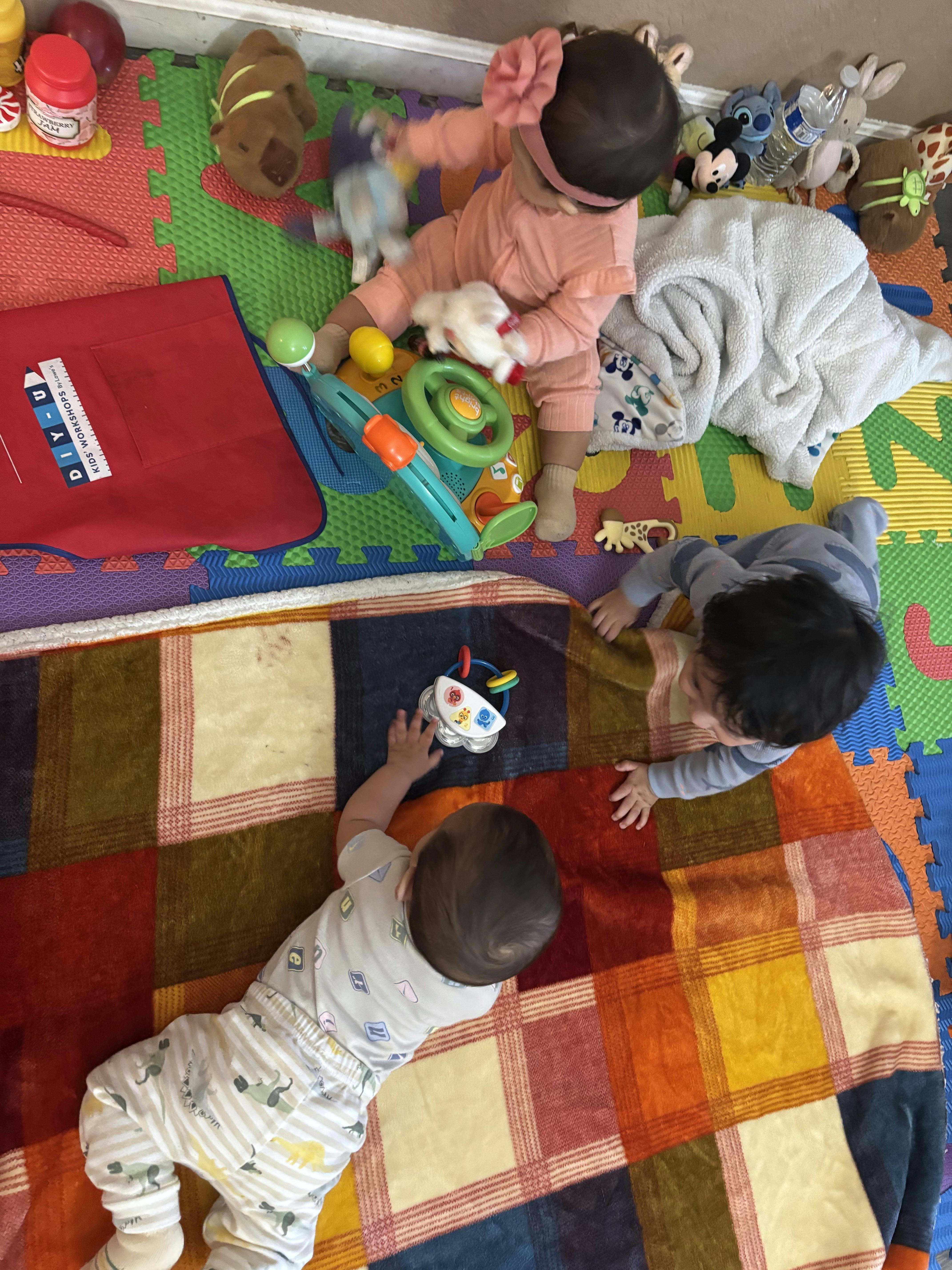 Three children playing with toys on a colorful mat
