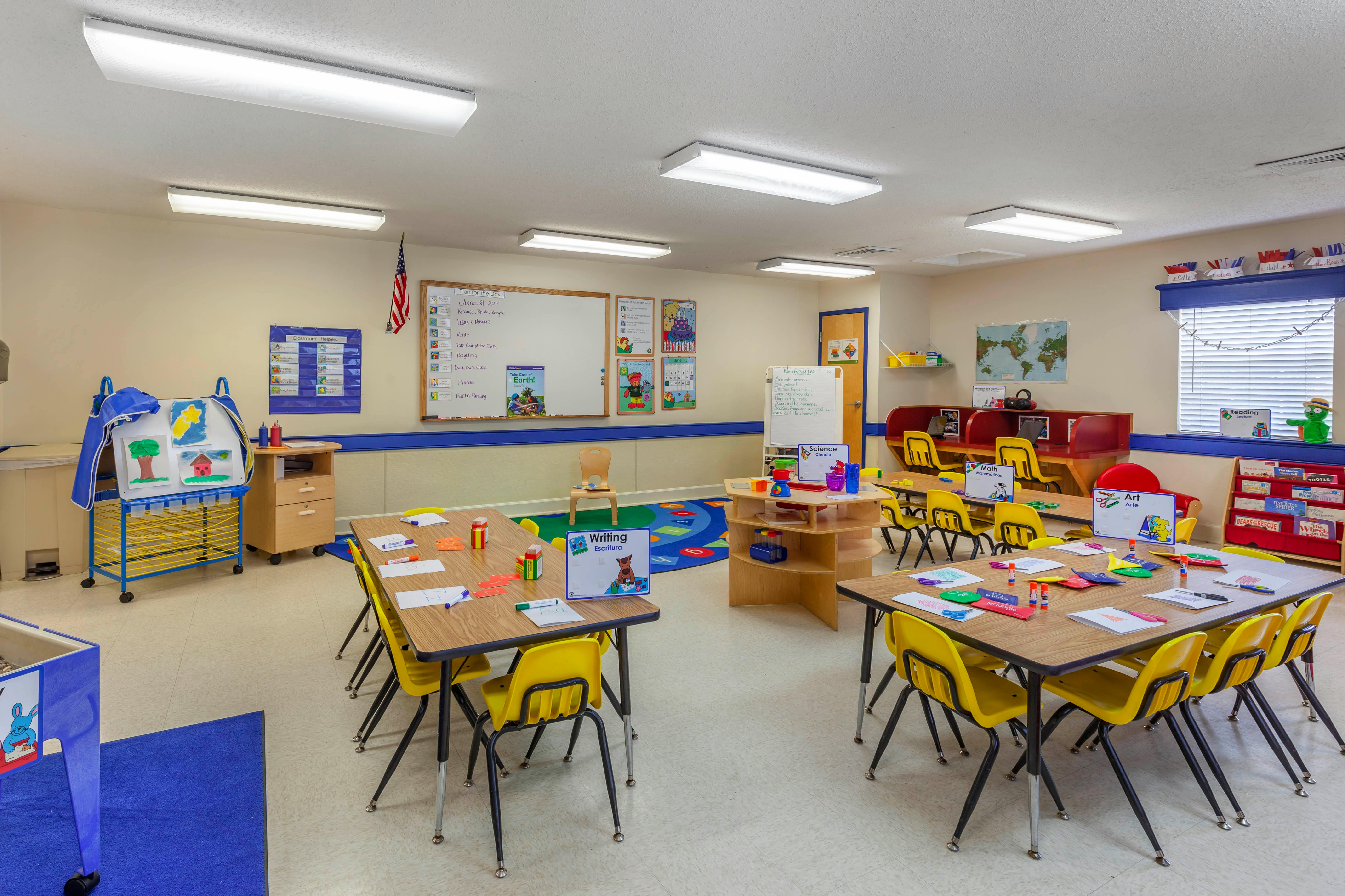 Classroom with small tables, yellow chairs, and learning materials