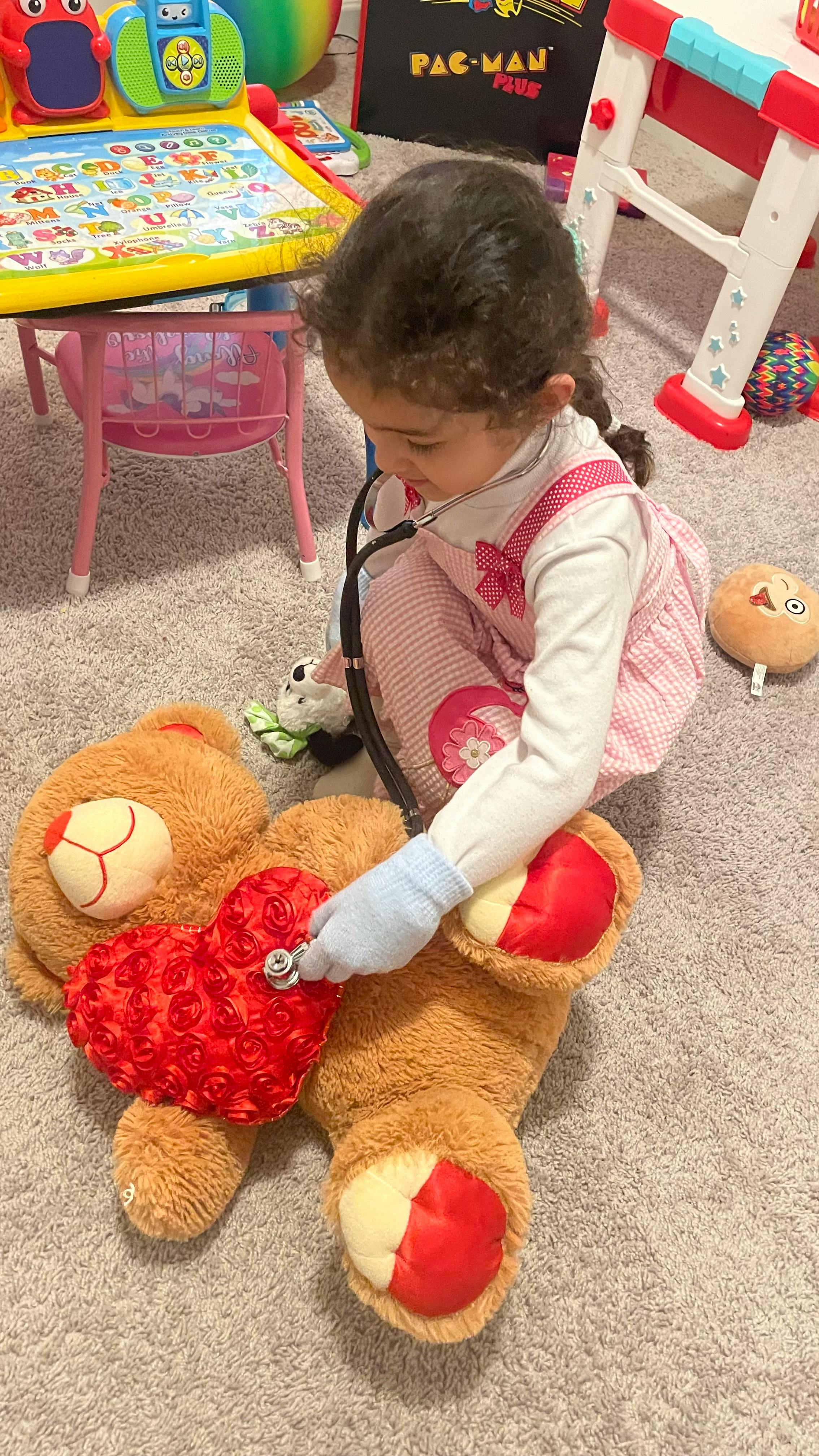 Child playing doctor with a stethoscope on a teddy bear