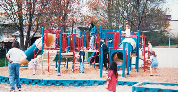Children playing on a playground structure with slides and tunnels