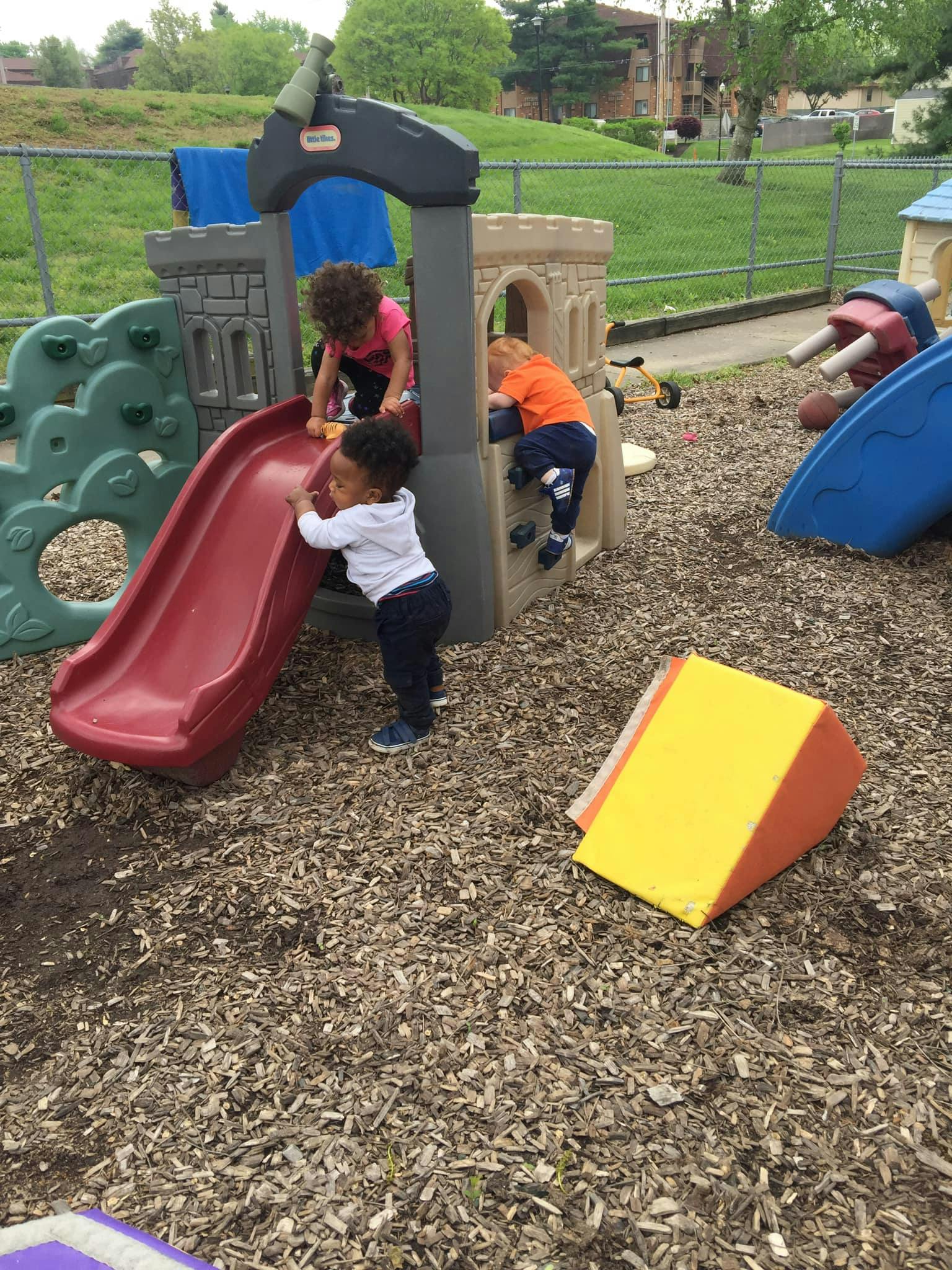 Three children playing on a playground structure with a slide