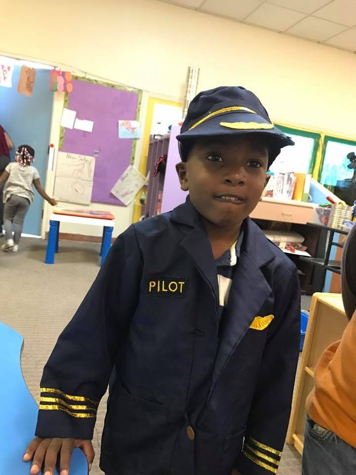 Child in a pilot costume with "PILOT" on the jacket
