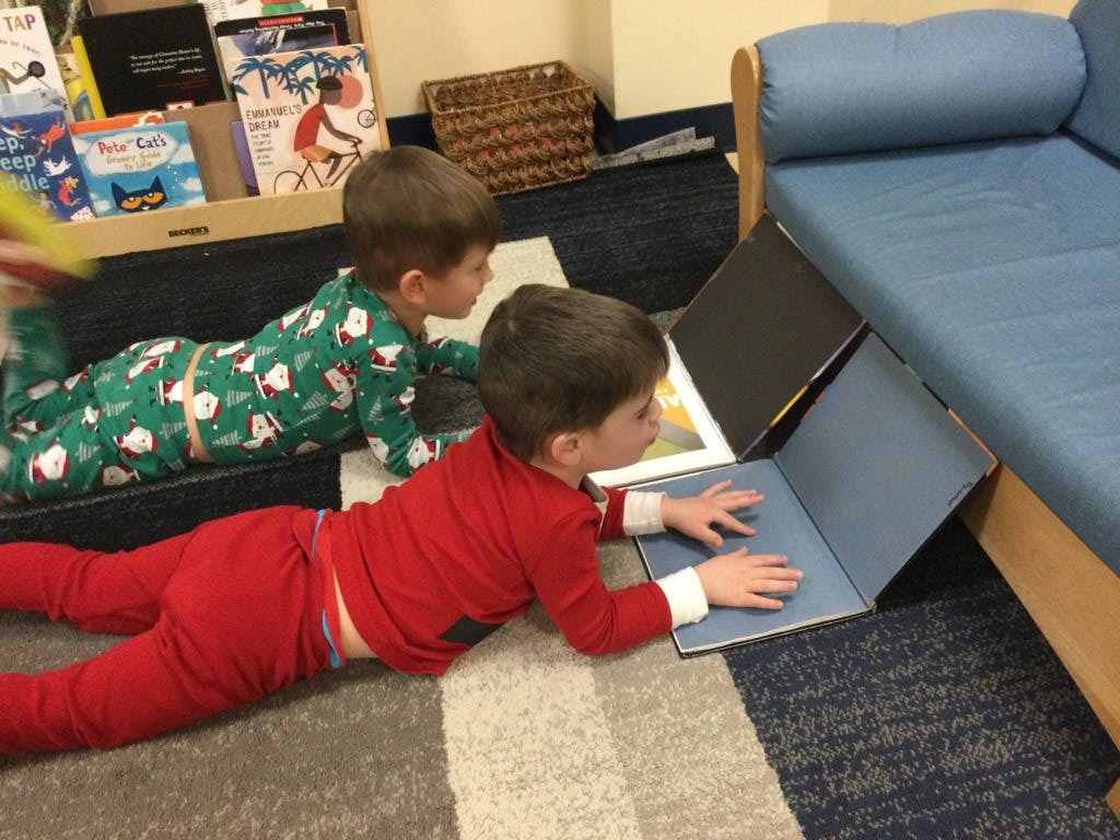 Two children lying on the floor looking at books