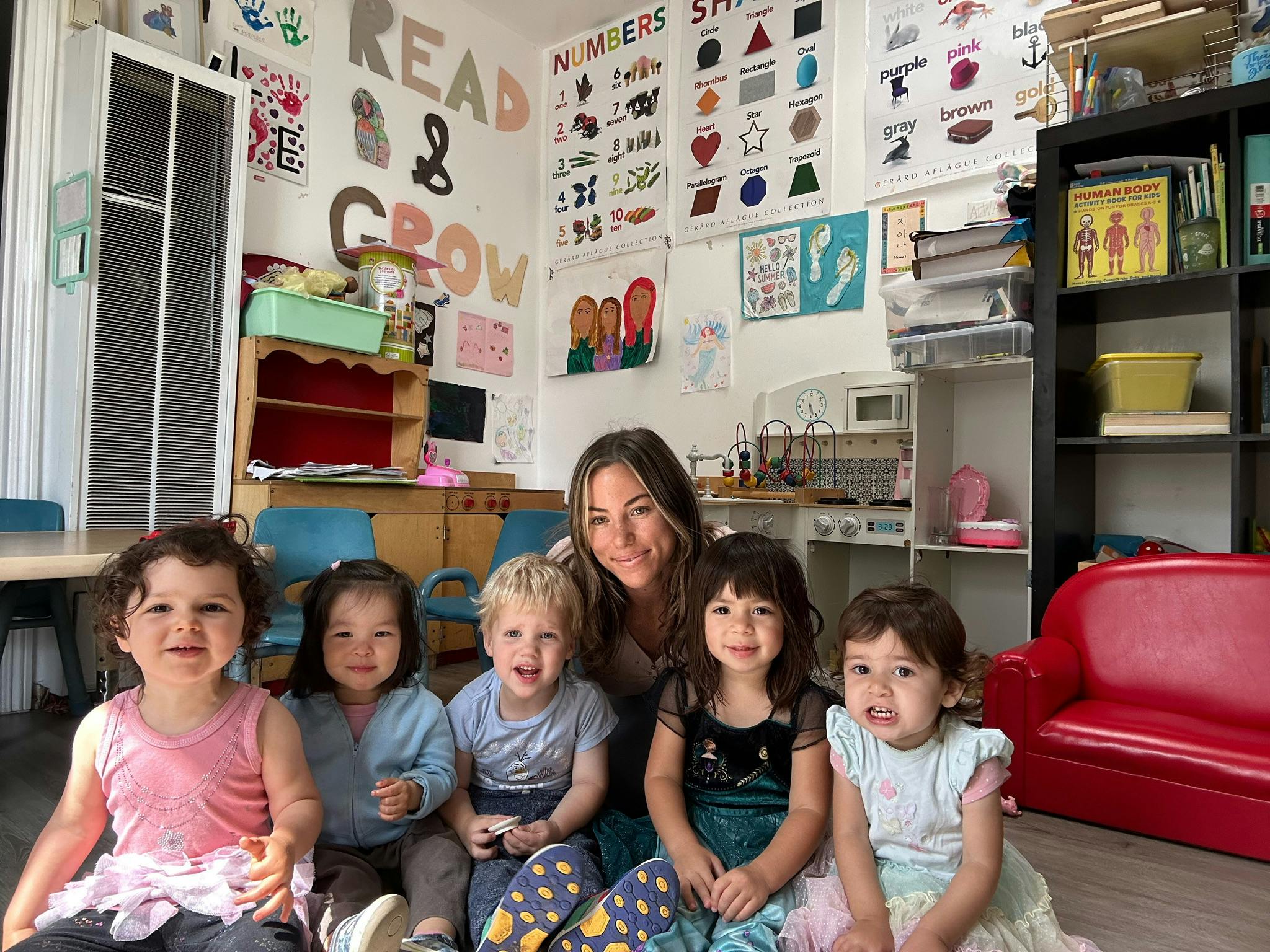 Adult and four children sitting on the floor in a classroom