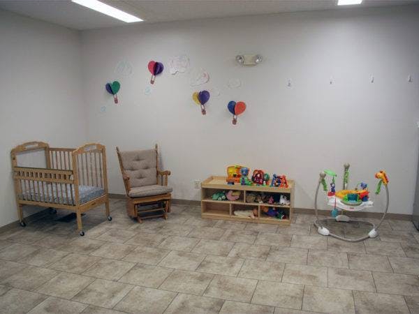 Nursery room with a crib, rocking chair, toy shelf, and baby bouncer