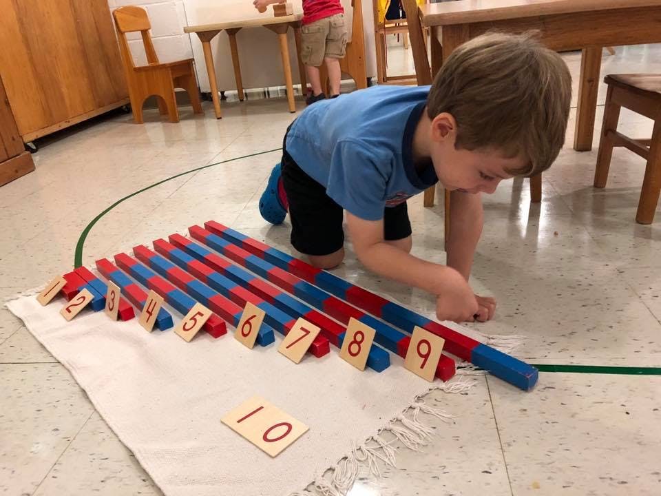 Child on floor with red and blue counting rods and number tiles