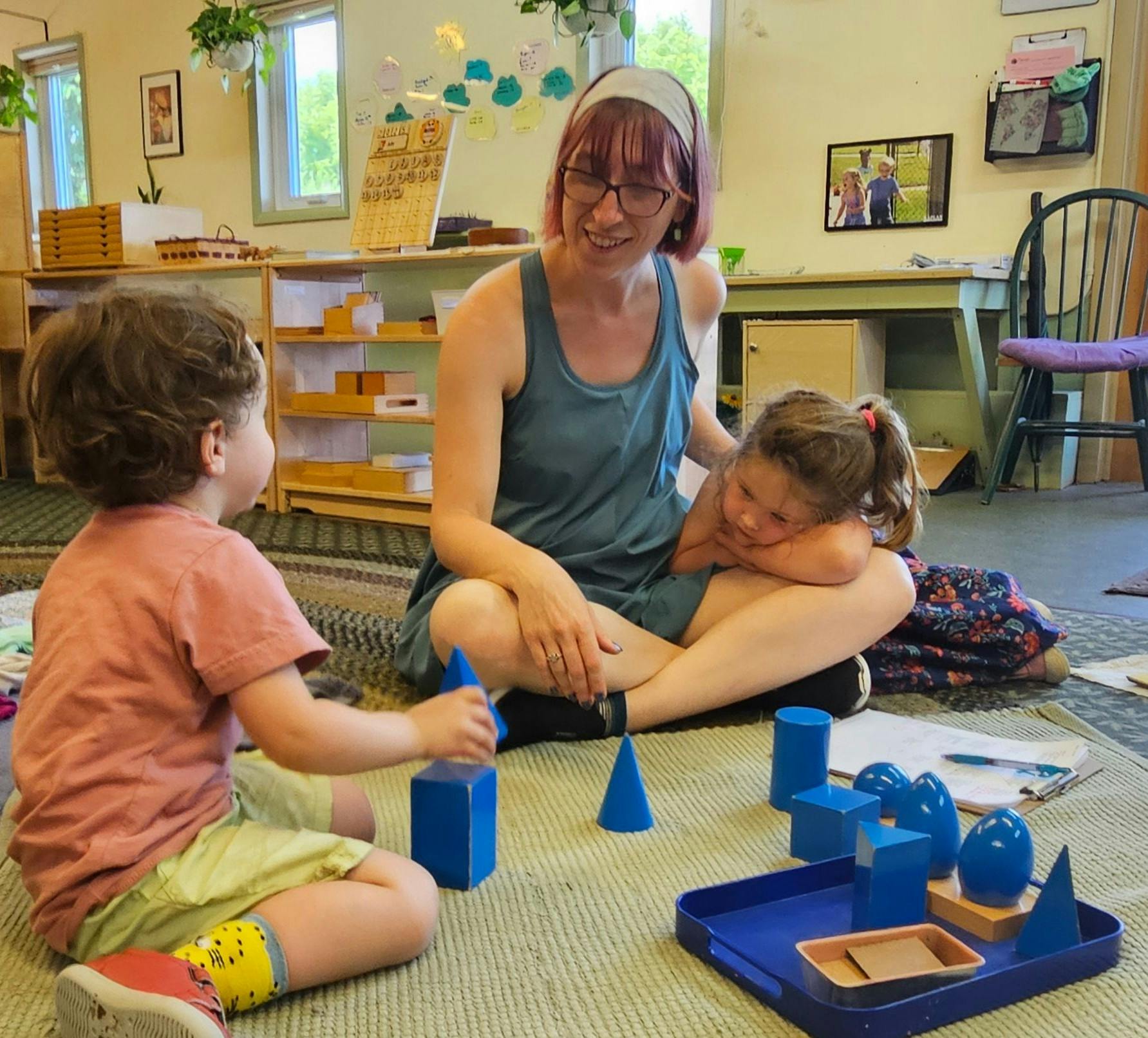 Adult and two children on floor with blue geometric shapes