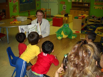 Person reading a book to children in a classroom