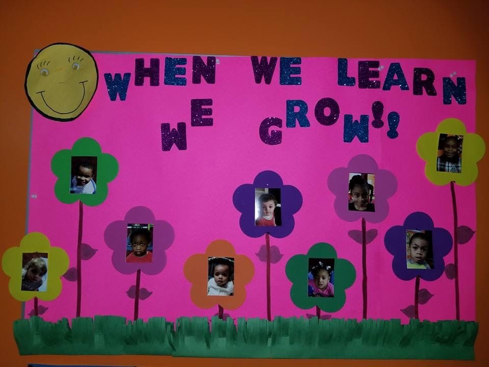 Bulletin board with "WHEN WE LEARN WE GROW!" and photos of children in flower cutouts