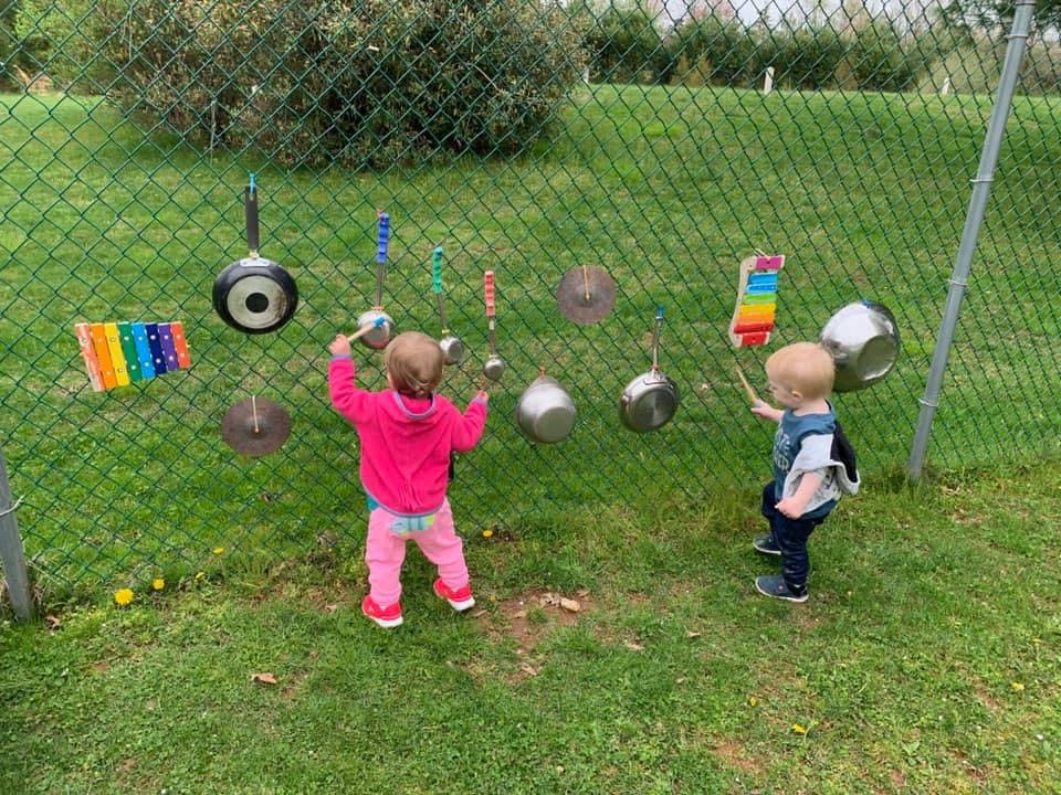 Two children playing with pots and pans on a fence