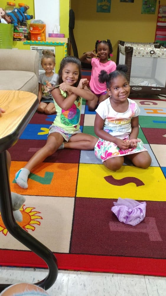 Four children sitting on a colorful alphabet rug