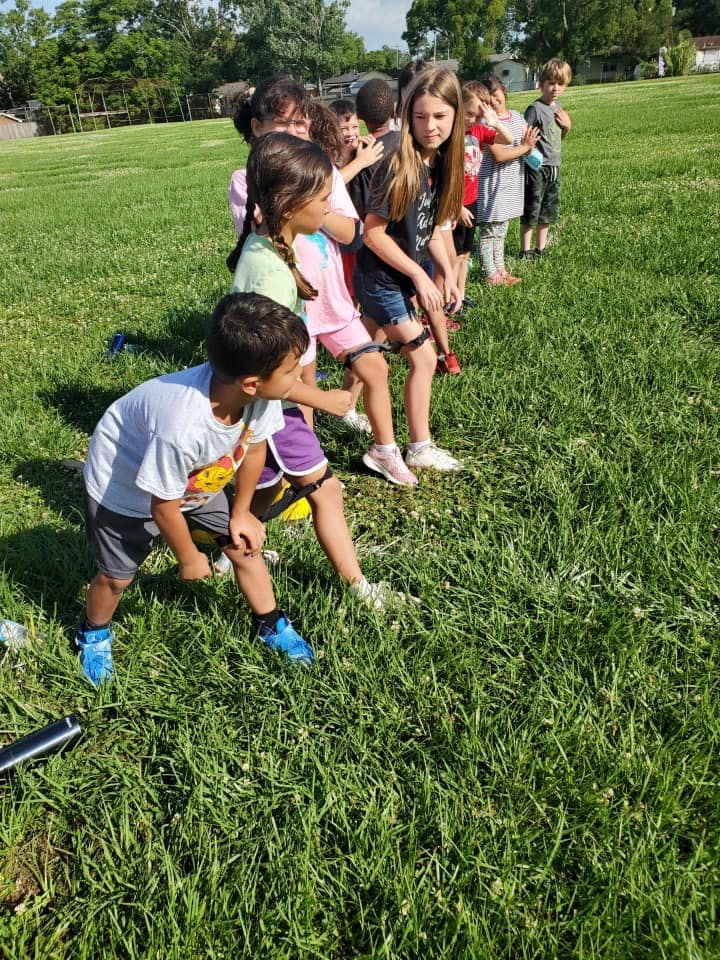 Children in a line on a grassy field