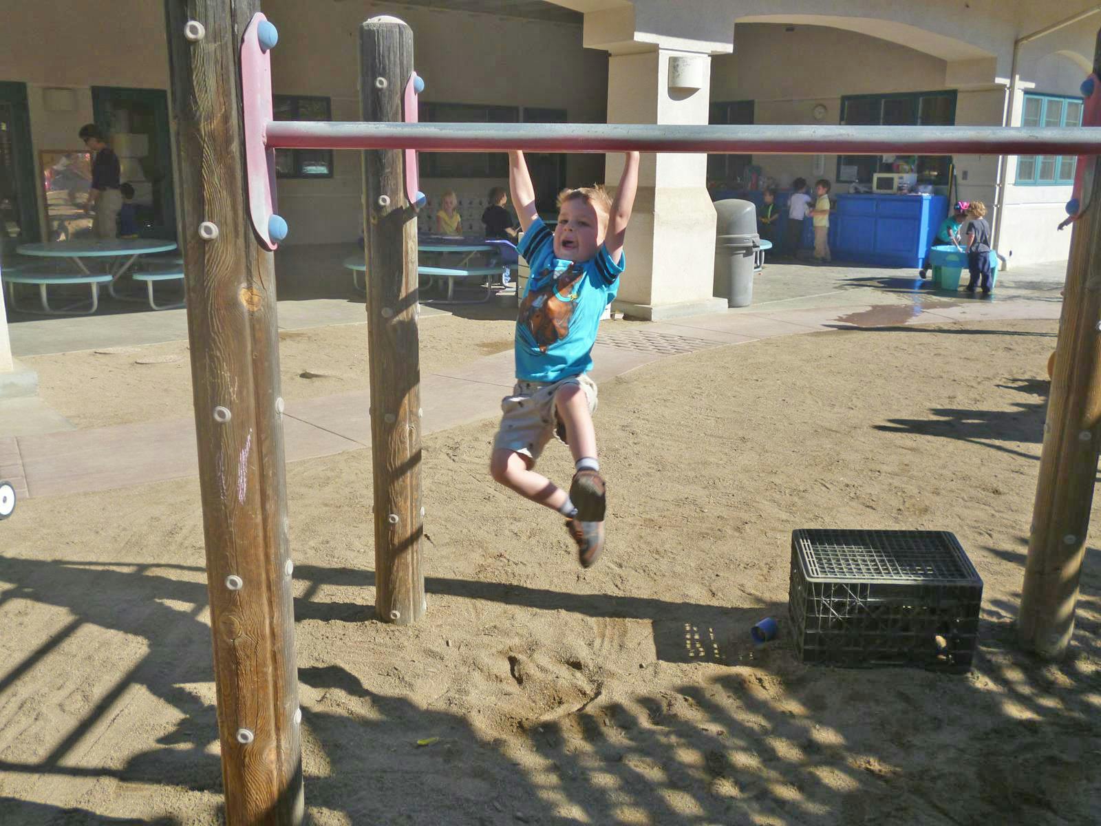 Child hanging from a monkey bar on a playground