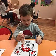 Child using a squeeze bottle to dot paint a drawing at a table