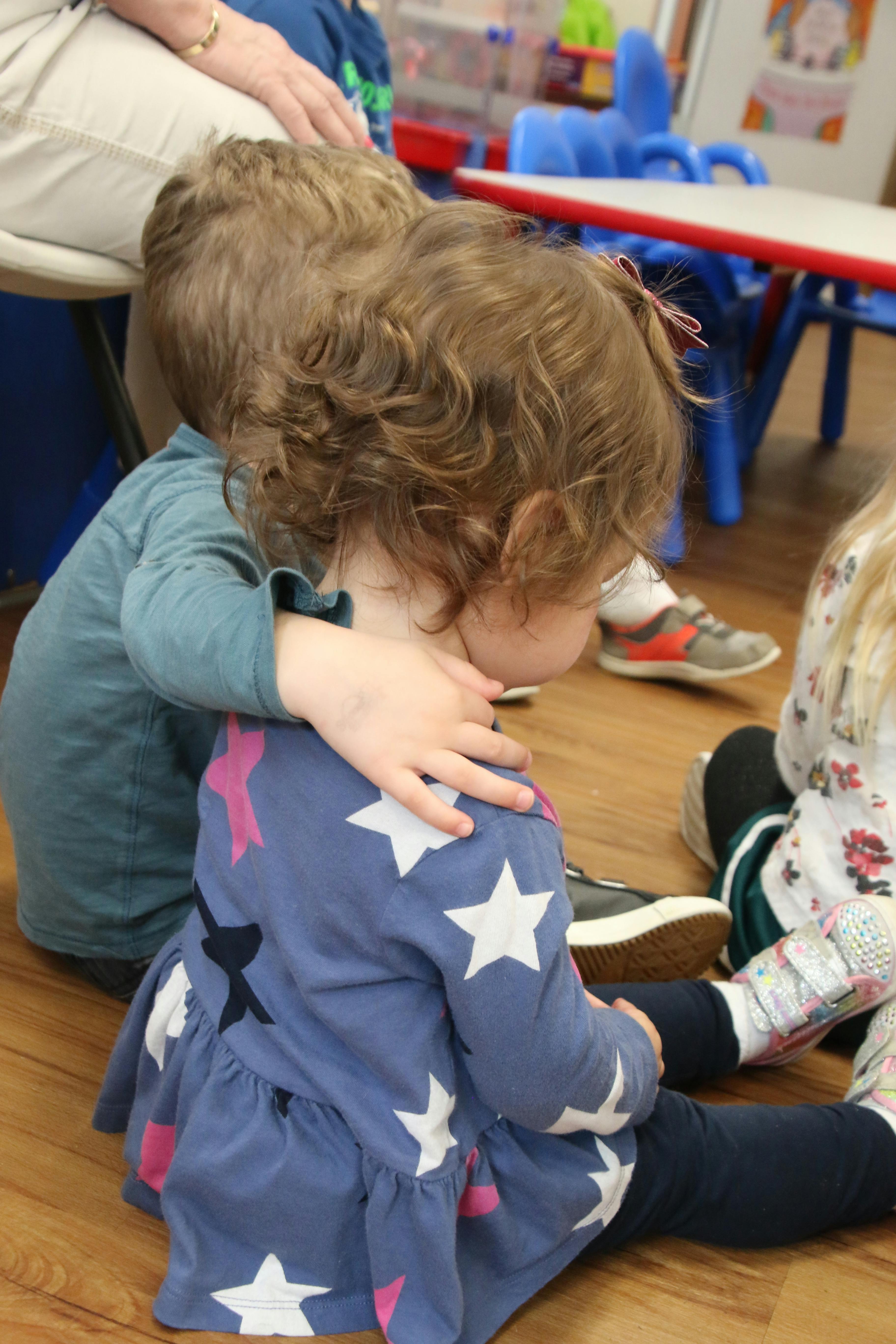 Child with arm around another child in a classroom