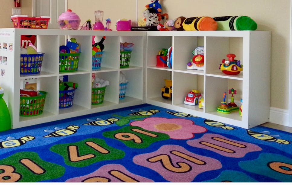 White storage shelves with toys and baskets on a colorful rug