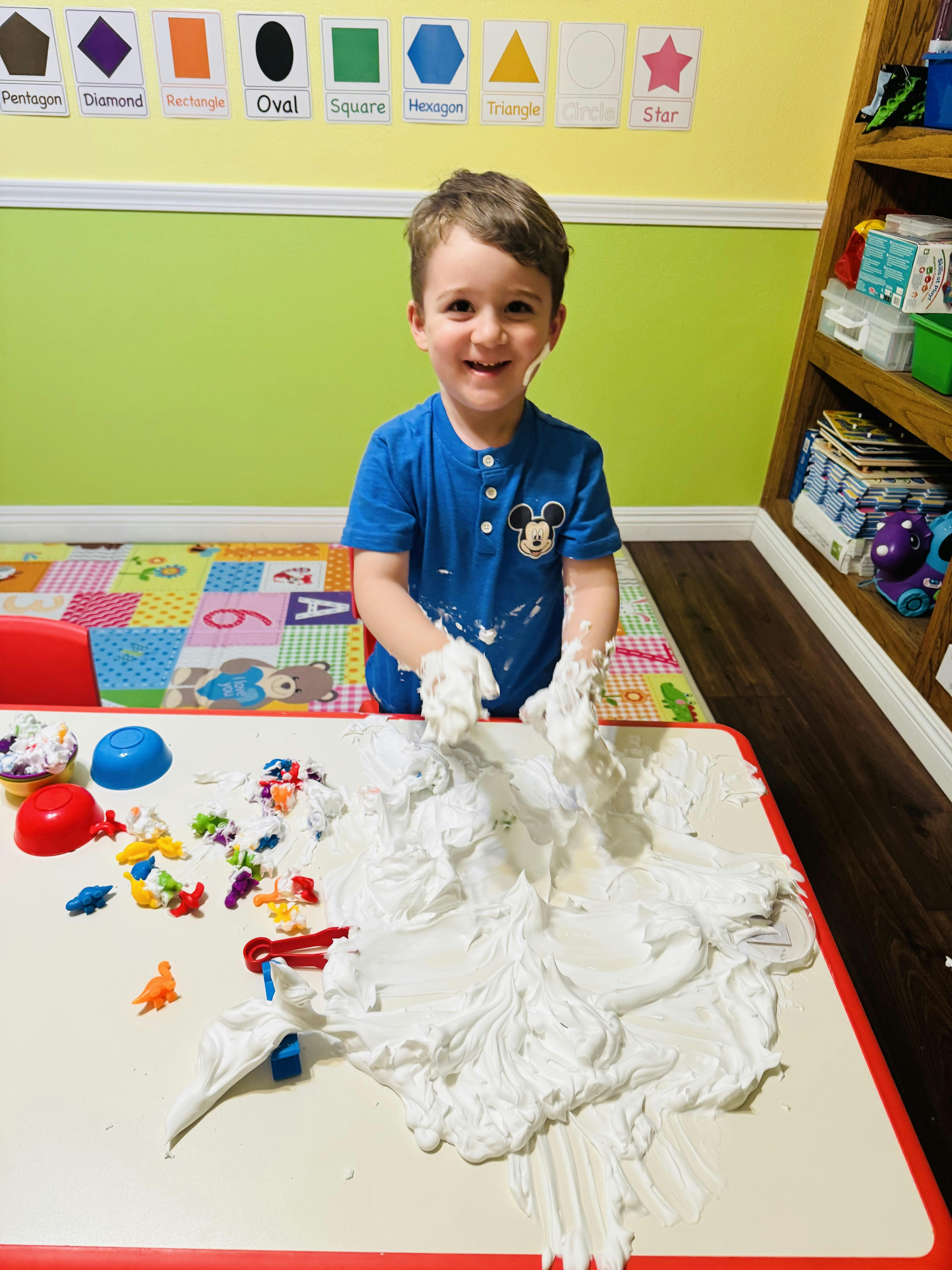 Child playing with shaving cream on a table