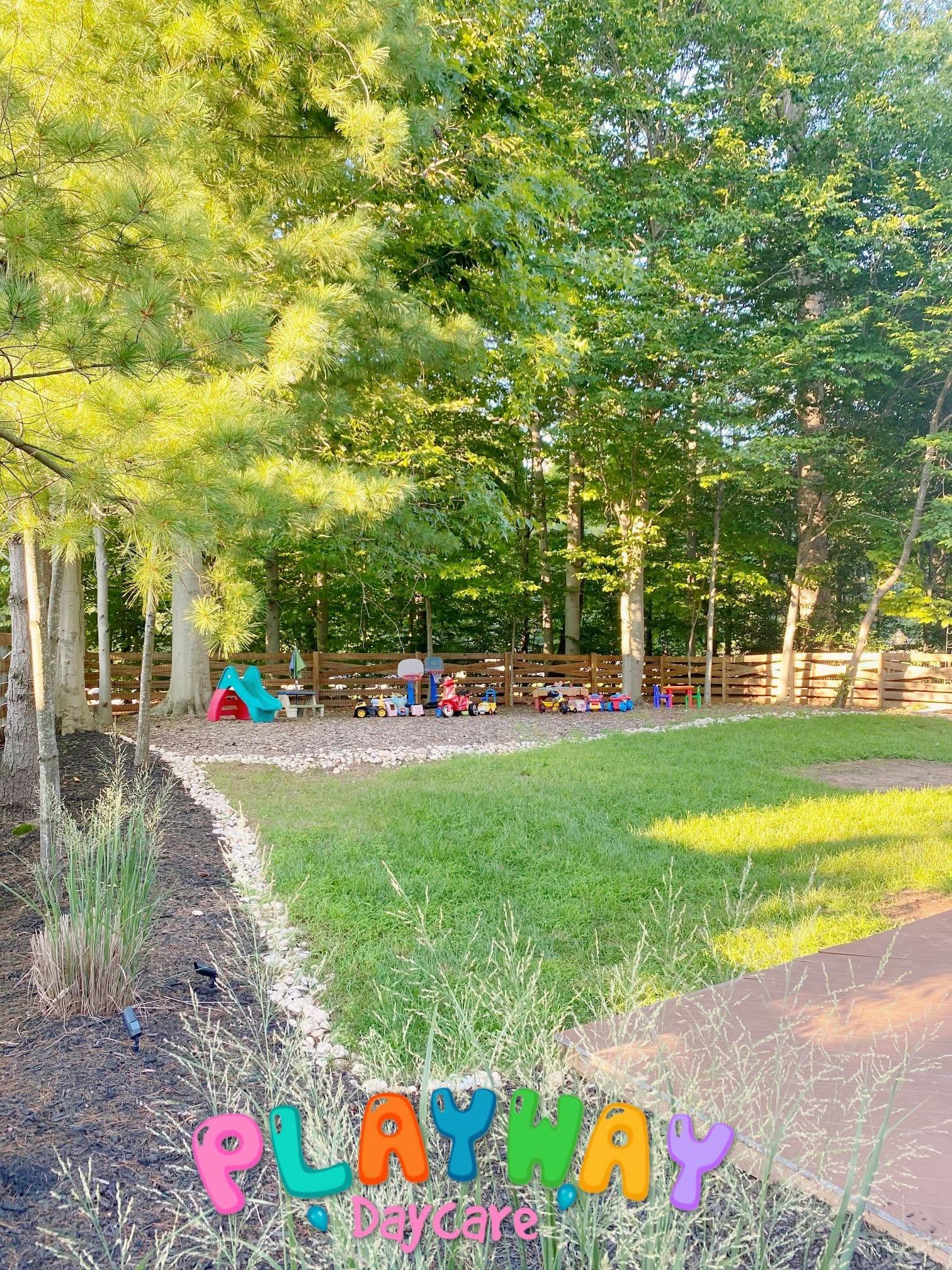 Outdoor play area with a slide and toys next to a grassy field