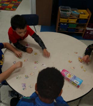 Children playing with small items at a round table