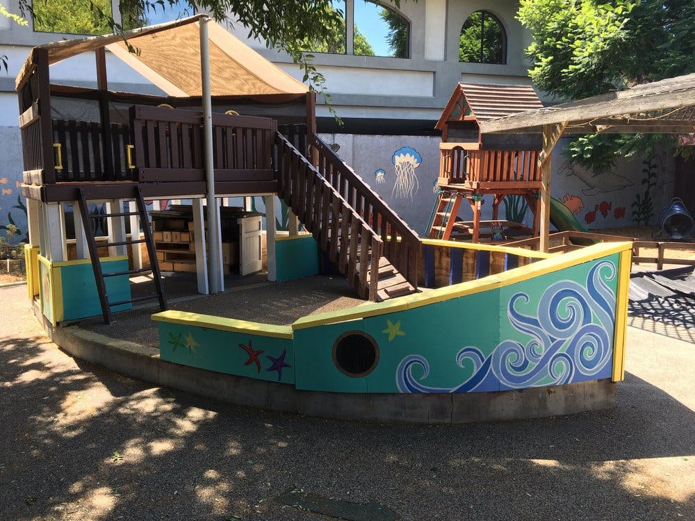 Playground structure shaped like a boat with a slide and stairs