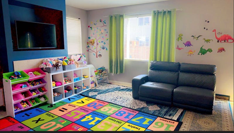 Playroom with colorful rug, toy storage, and sofa