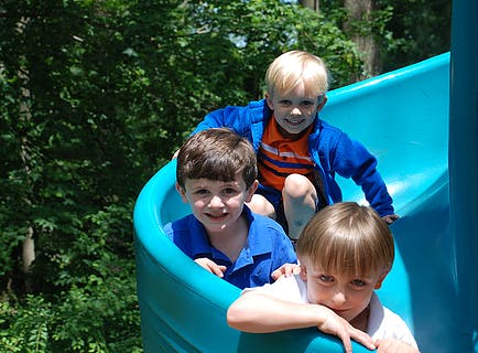 Three children on a blue playground slide