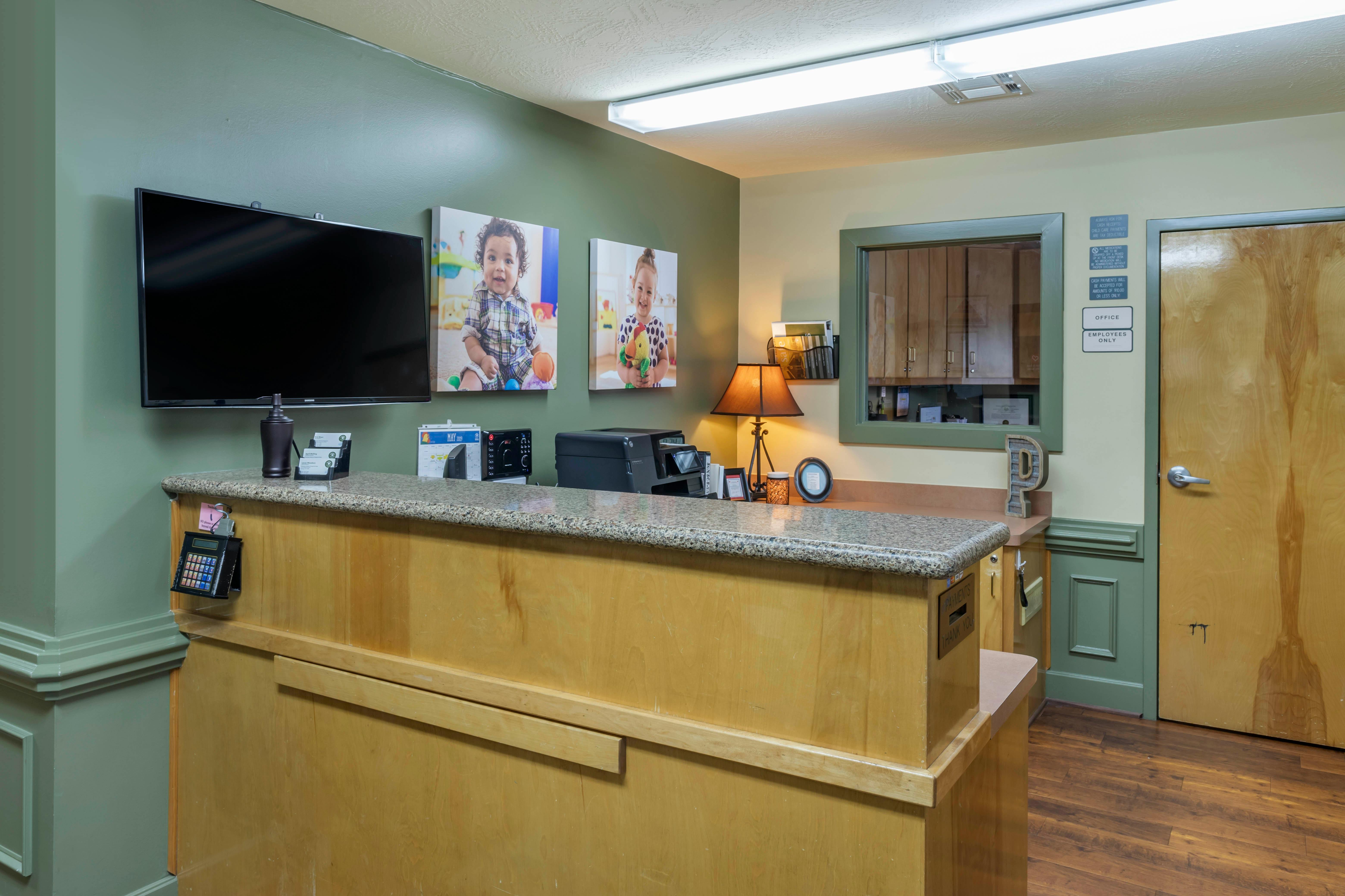 Reception desk with a television, framed photos of children, and office items