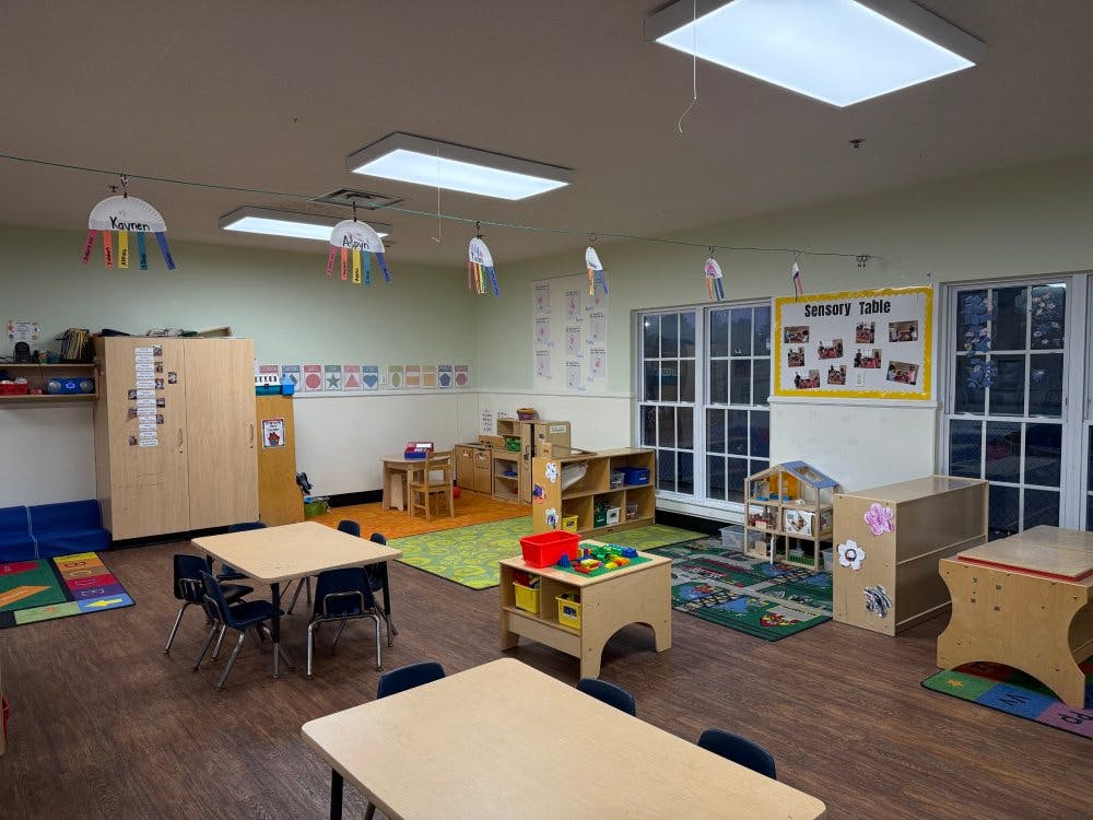 Empty classroom with small tables and chairs, toys, and children's decorations