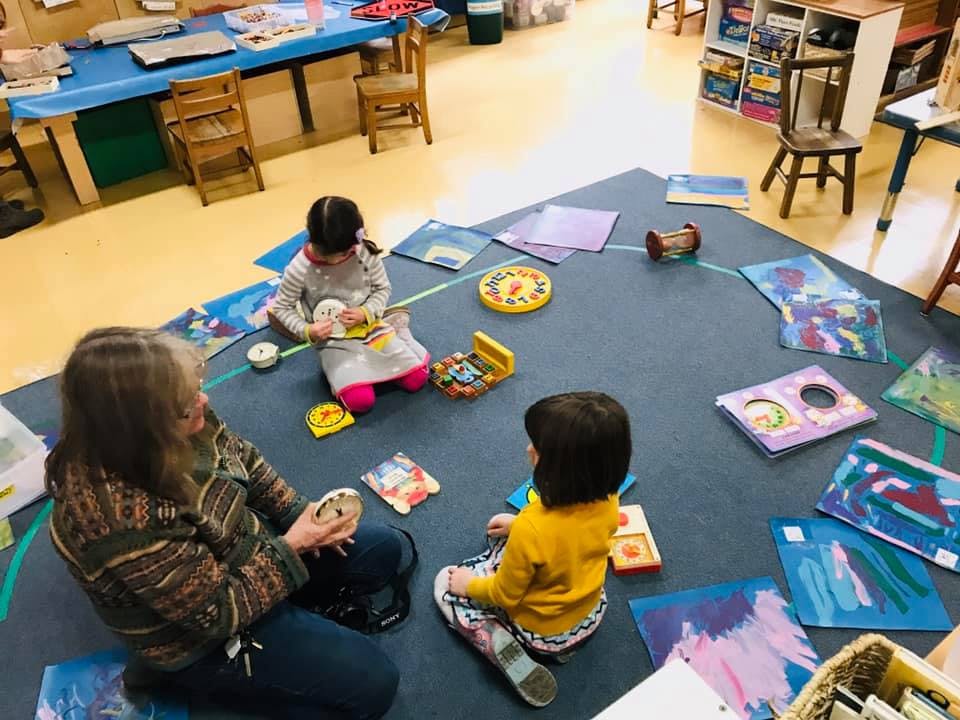 Adult and two children sitting on a rug with art supplies