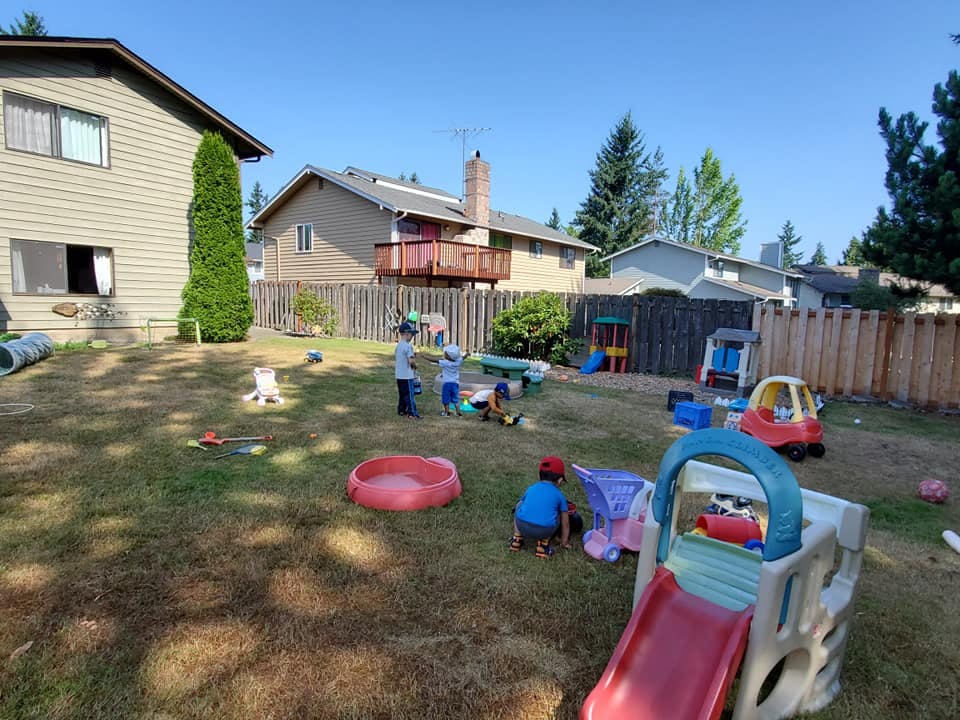 Children playing in a backyard with various toys and play structures