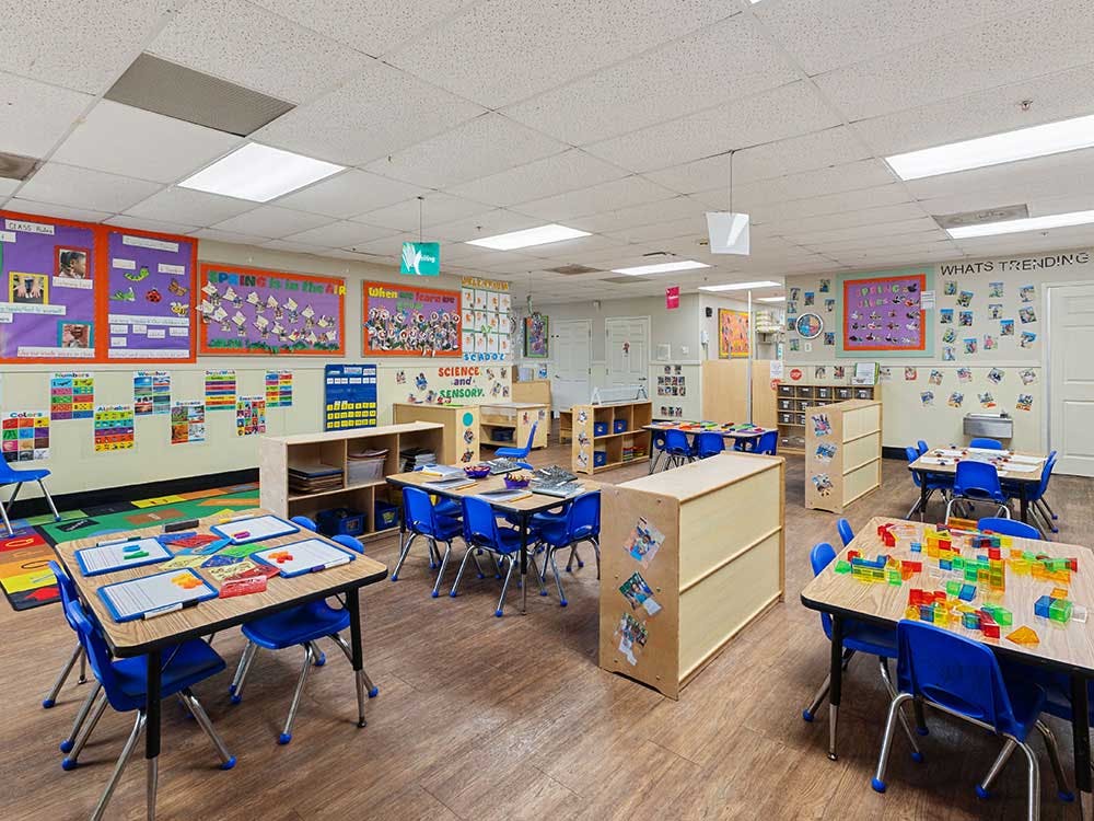 Empty classroom with small tables and chairs, and colorful decorations on the walls