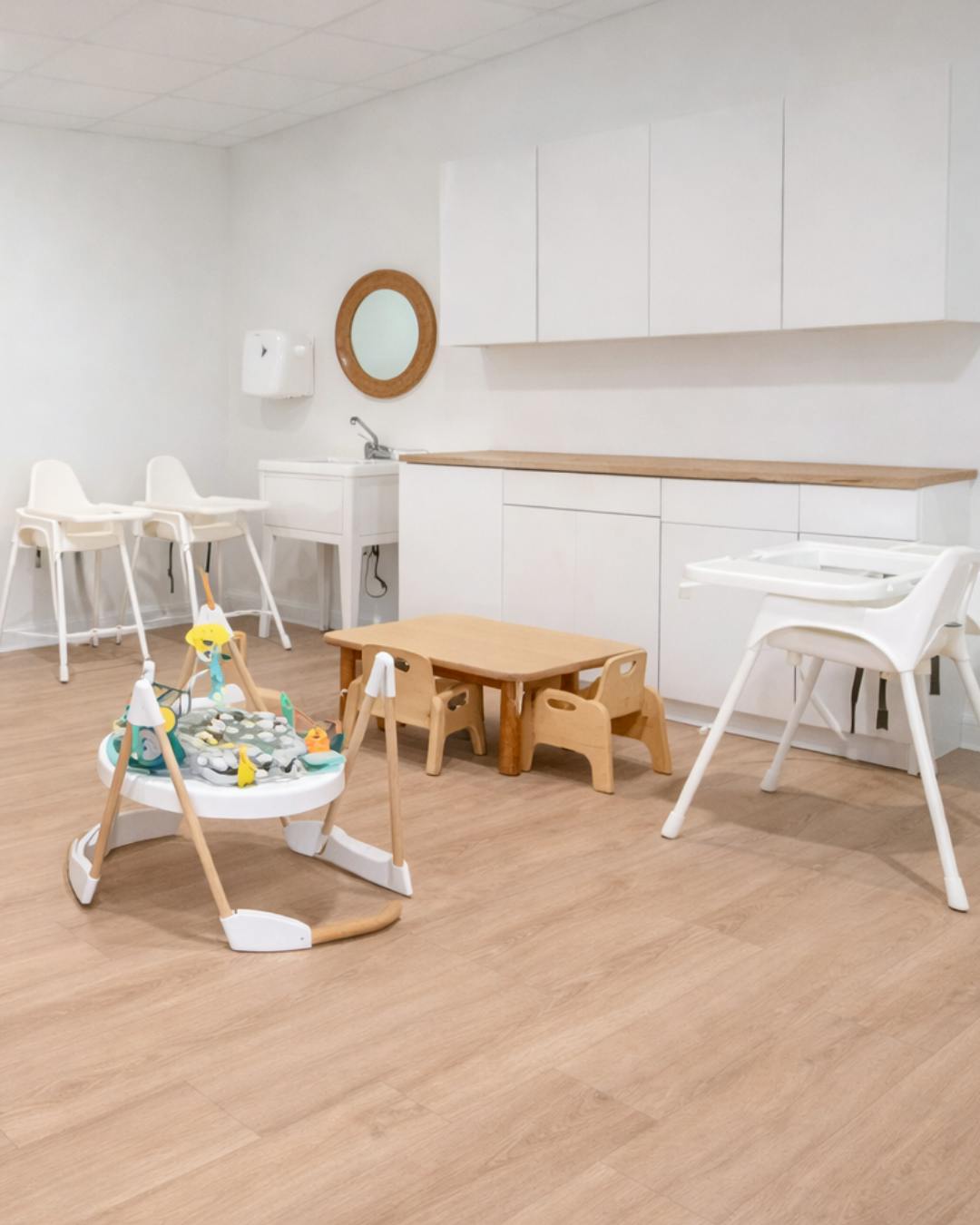 Baby high chairs, activity walker, small table with chairs, sink, and cabinets