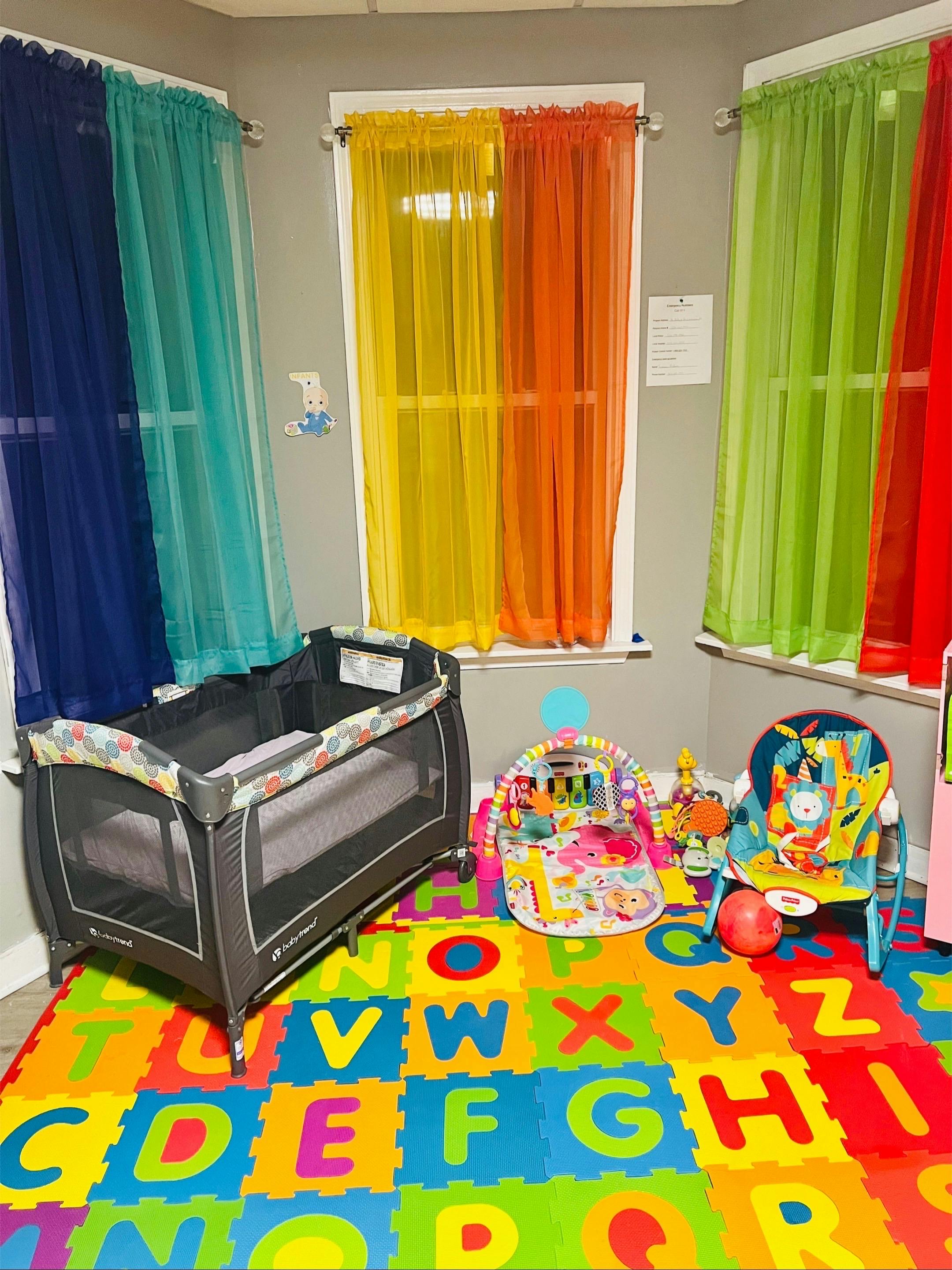 Playpen, baby activity mat, and bouncer on an alphabet floor mat