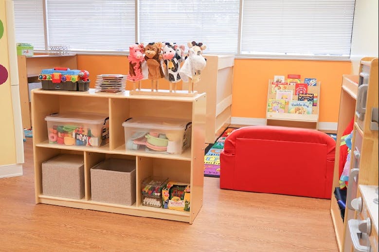 Classroom with wooden shelves, toys, and a red cushion