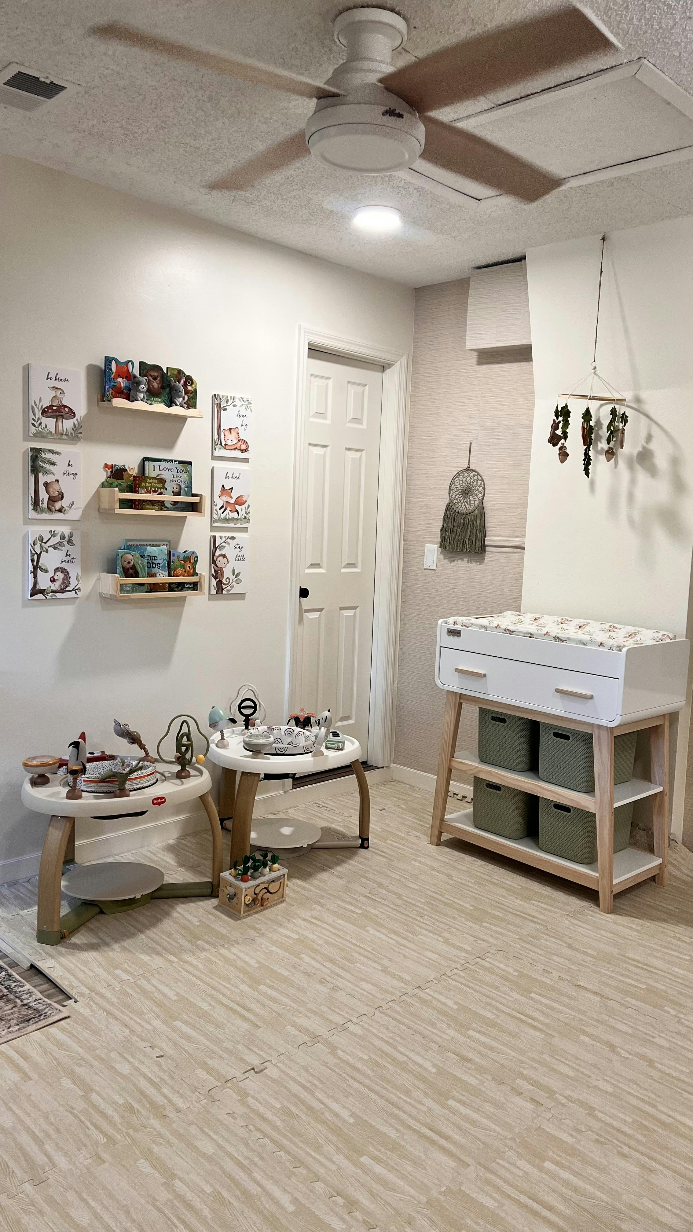 A room with a ceiling fan, two small tables, and a changing table