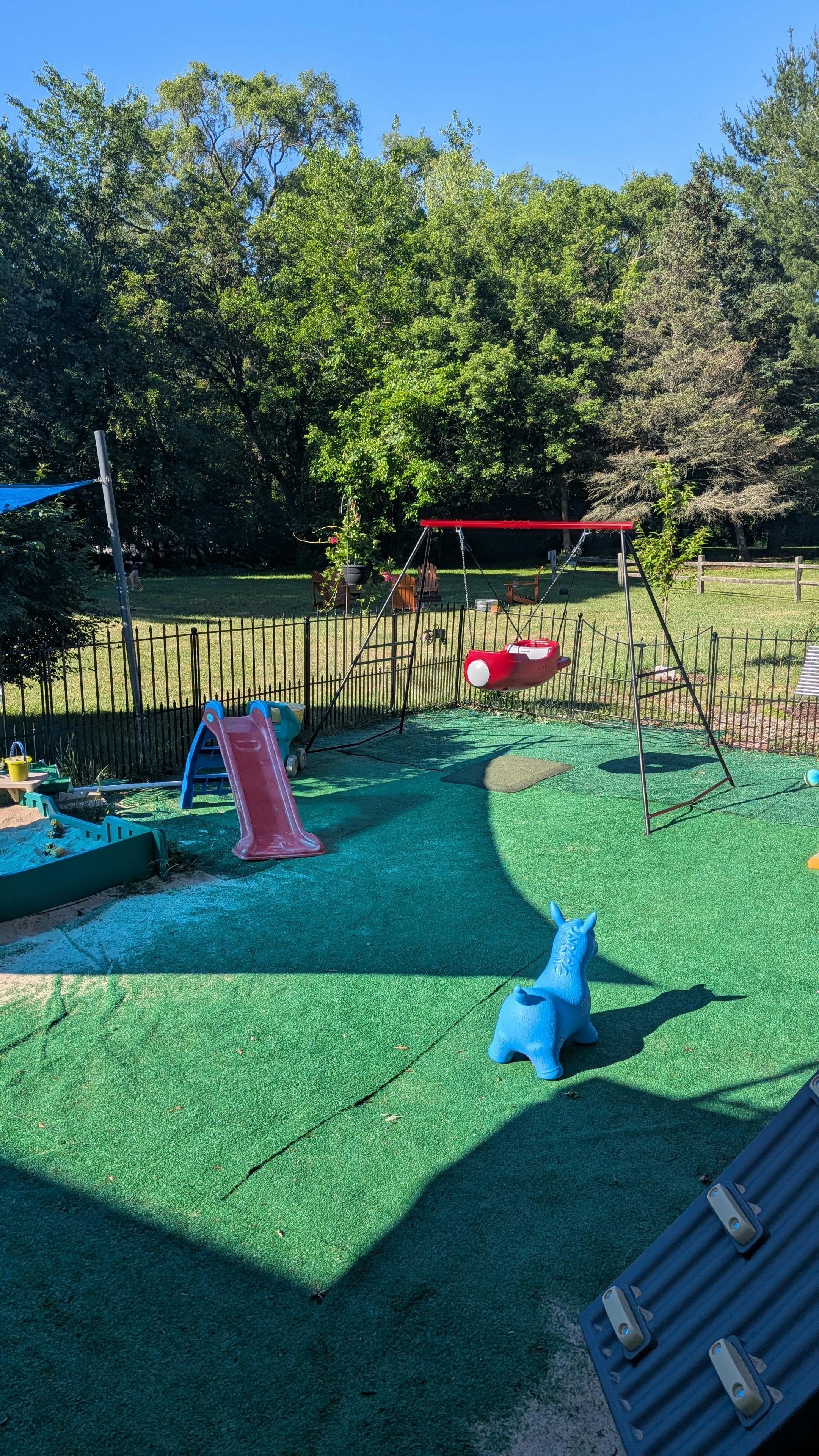 Playground equipment including a slide, swing, and riding toy on a lawn