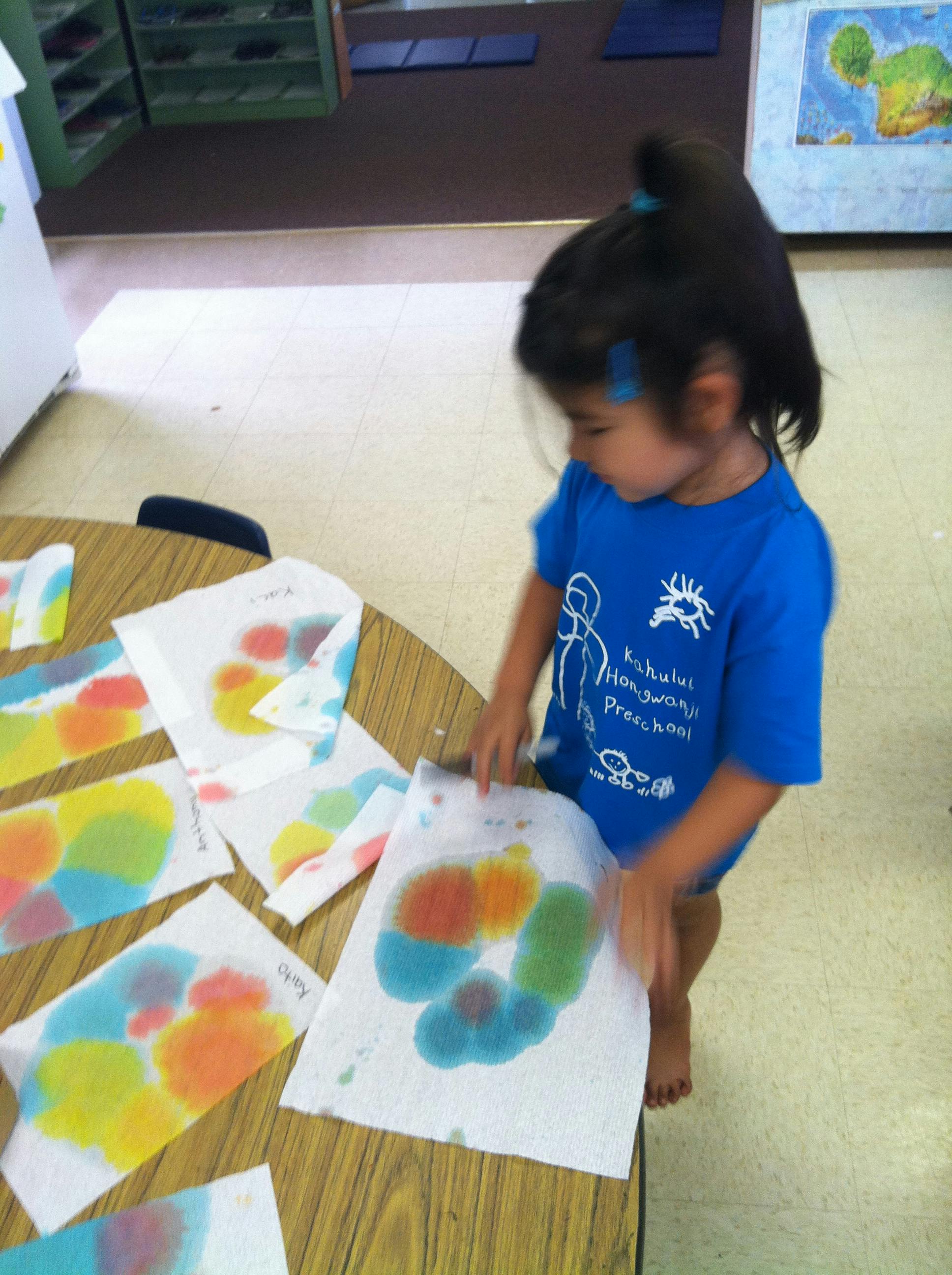 Child looking at colorful artwork on a table