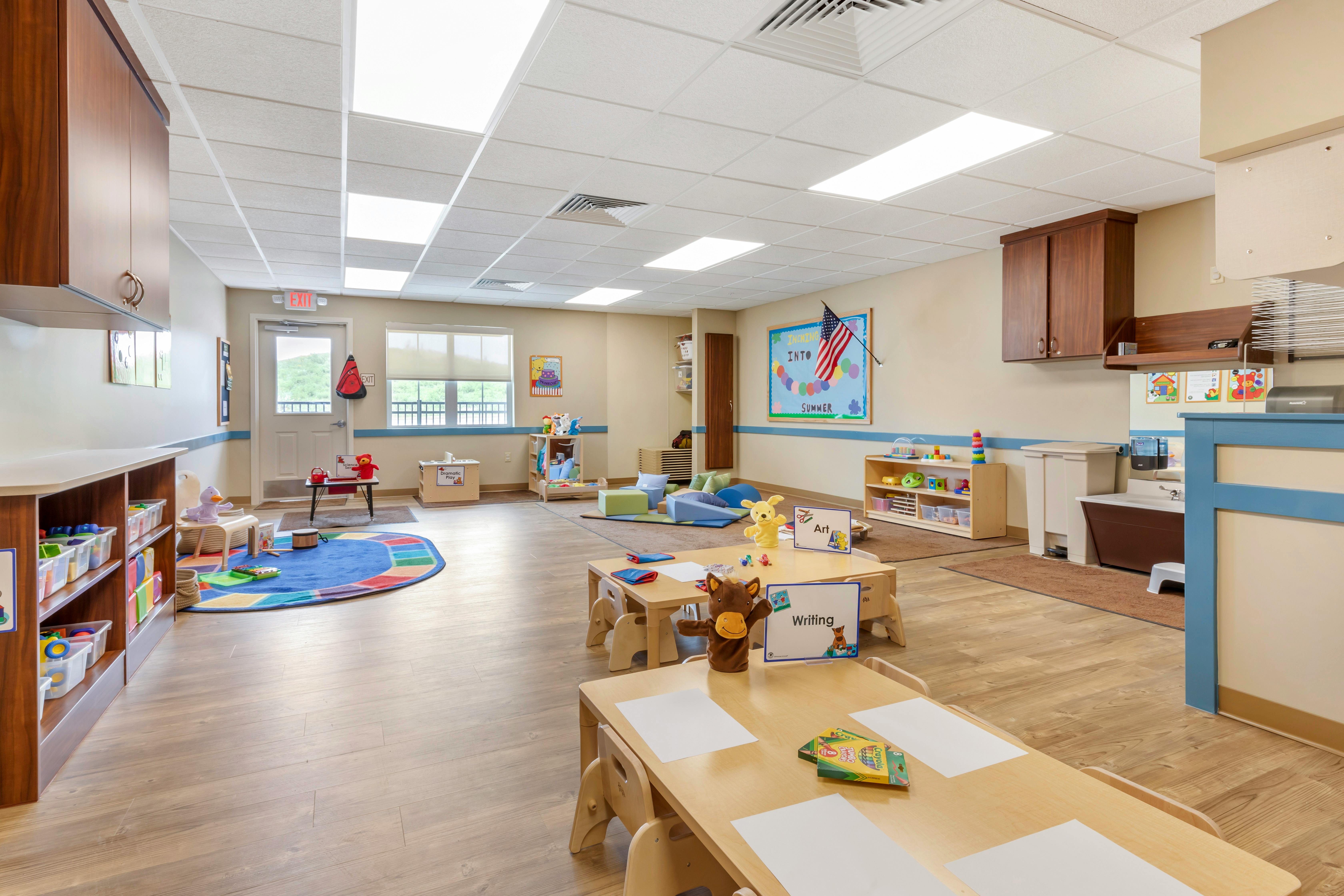 An empty early childhood classroom with multiple learning stations and small tables
