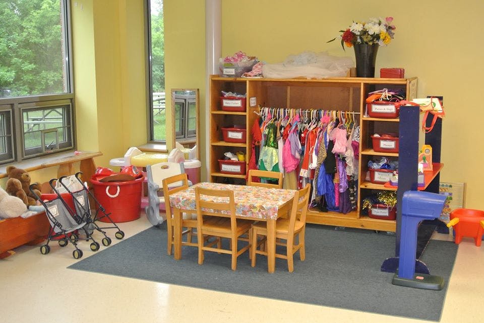 Children's play area with small table and chairs, dress-up clothes rack