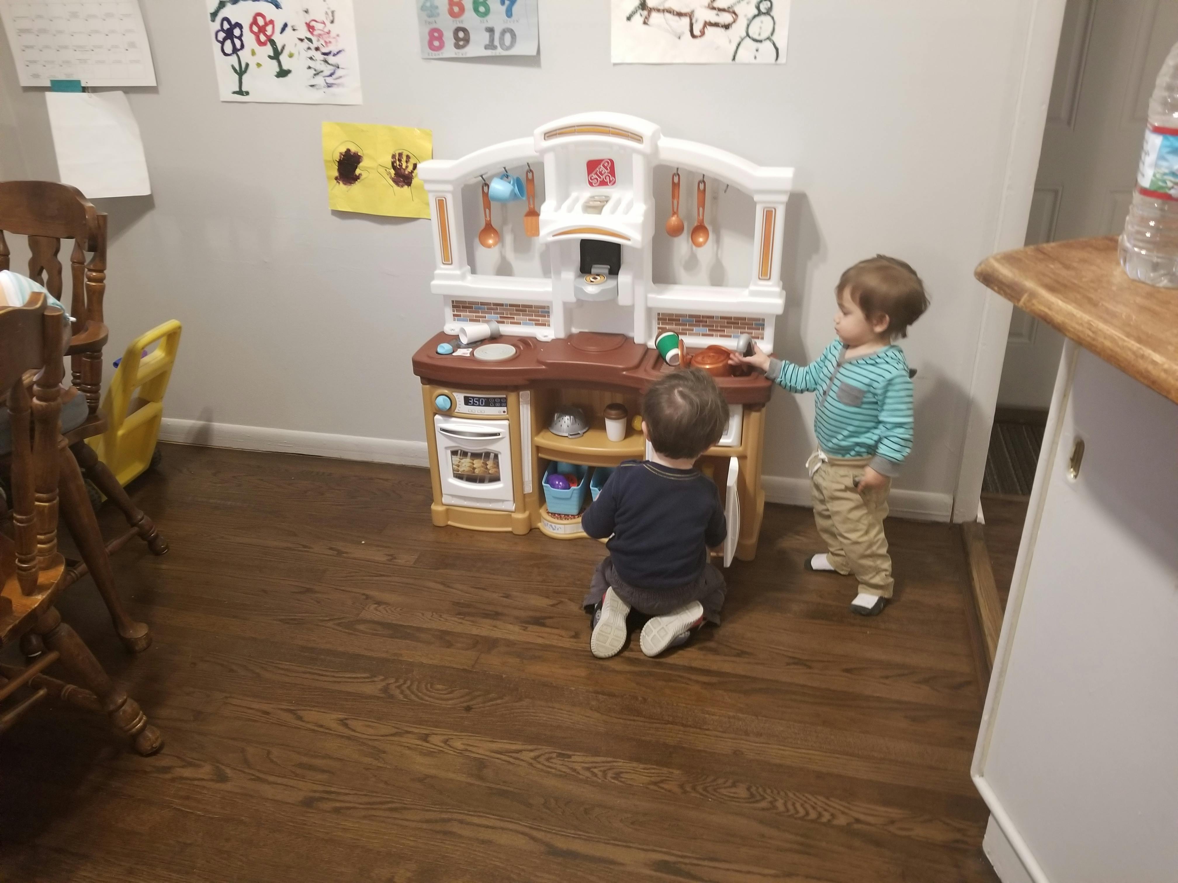 Two children playing with a toy kitchen set