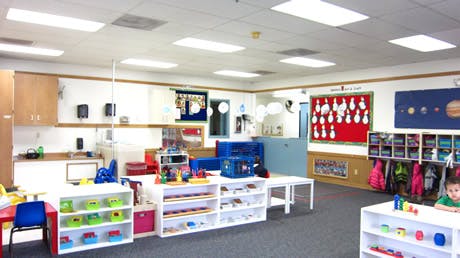 Classroom with shelves, tables, and a child