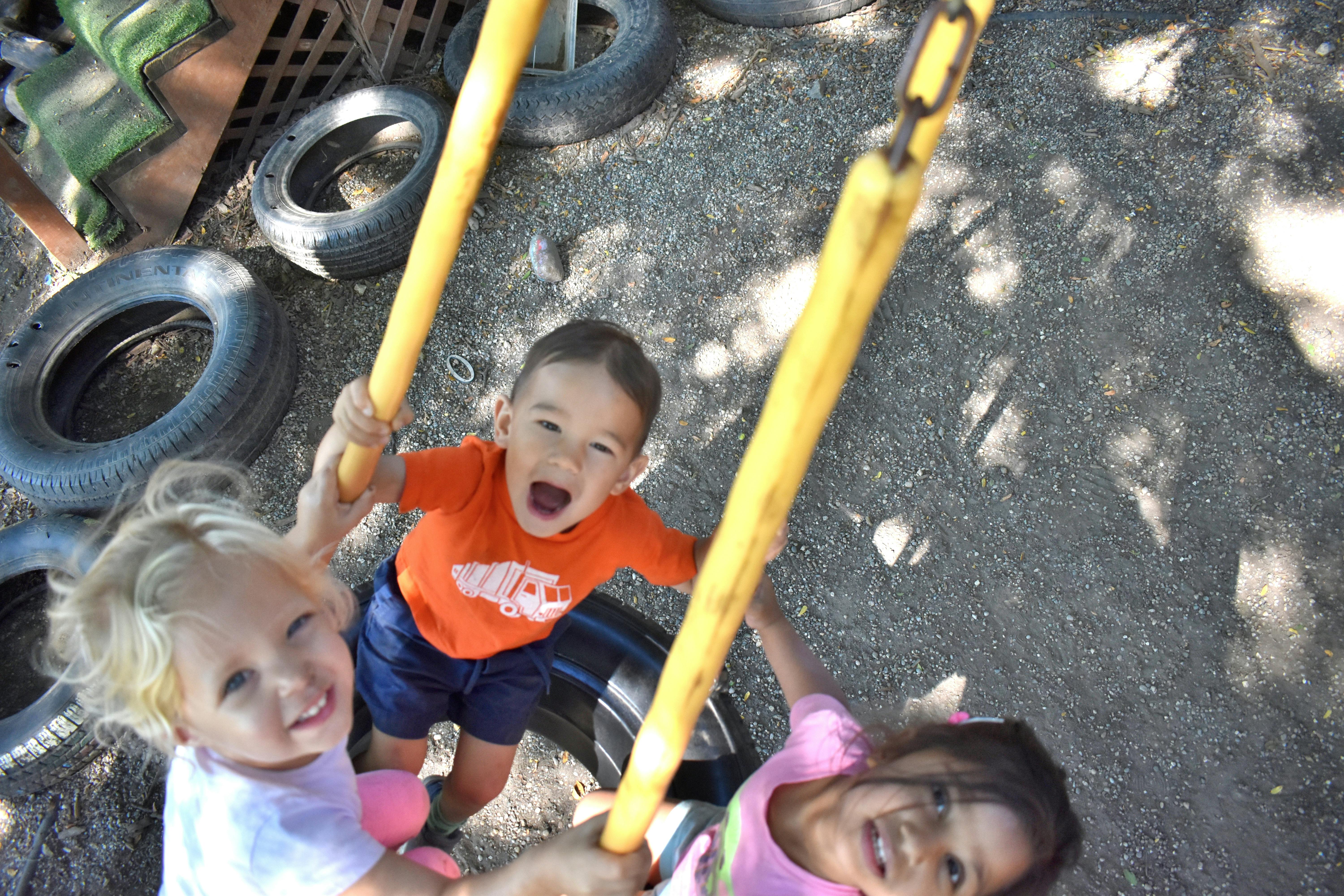 Three children playing on a swing set