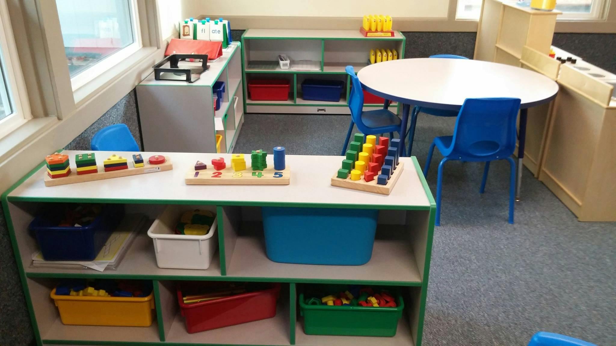 Classroom with shelves of toys and a round table with blue chairs