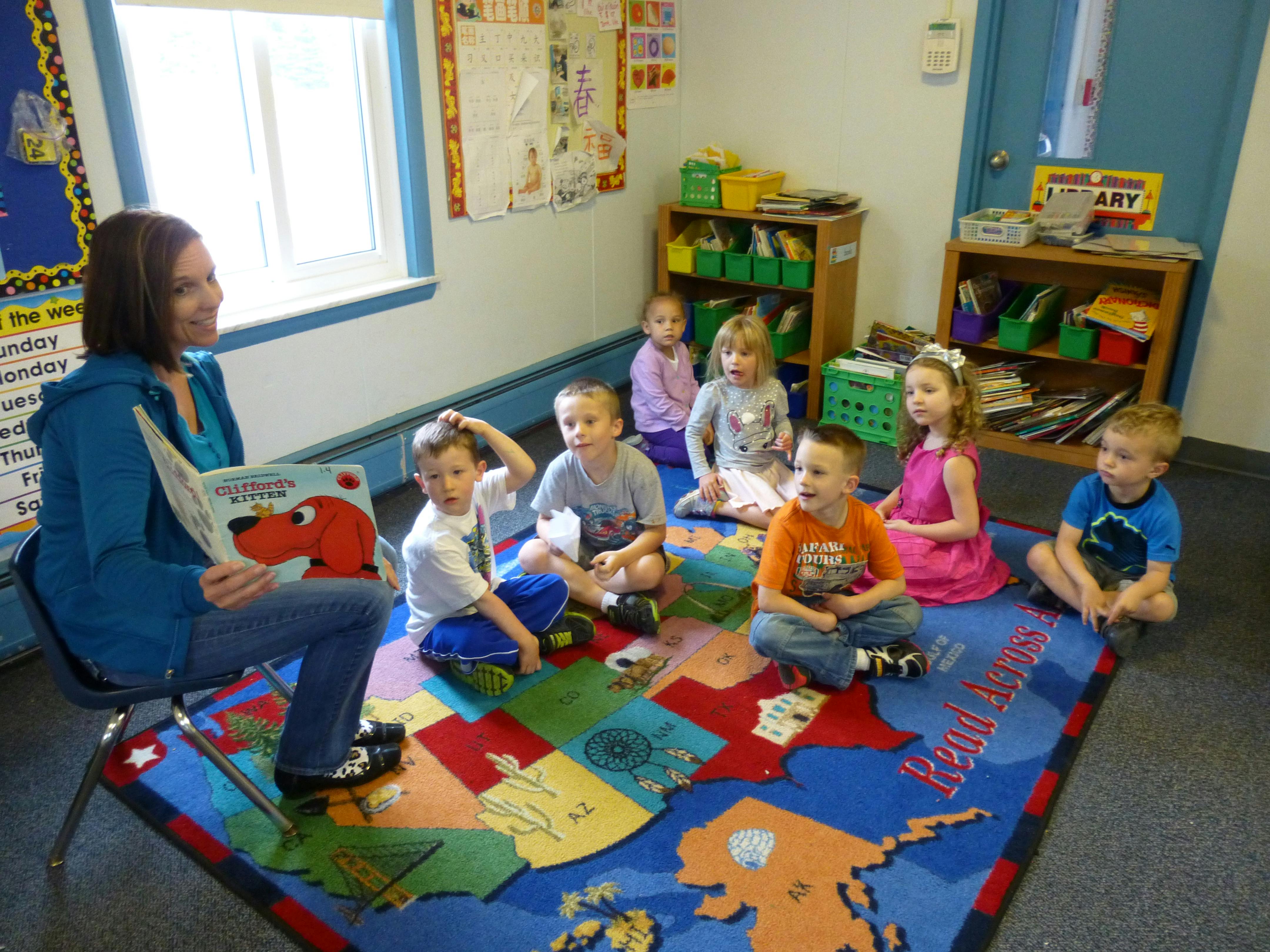 Person reading a book to a group of children in a classroom