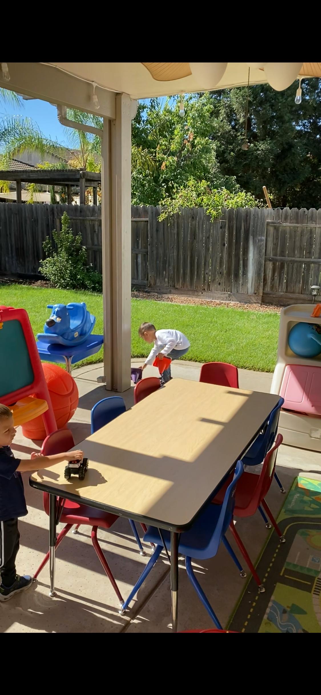 Child playing with a toy truck at a table outdoors